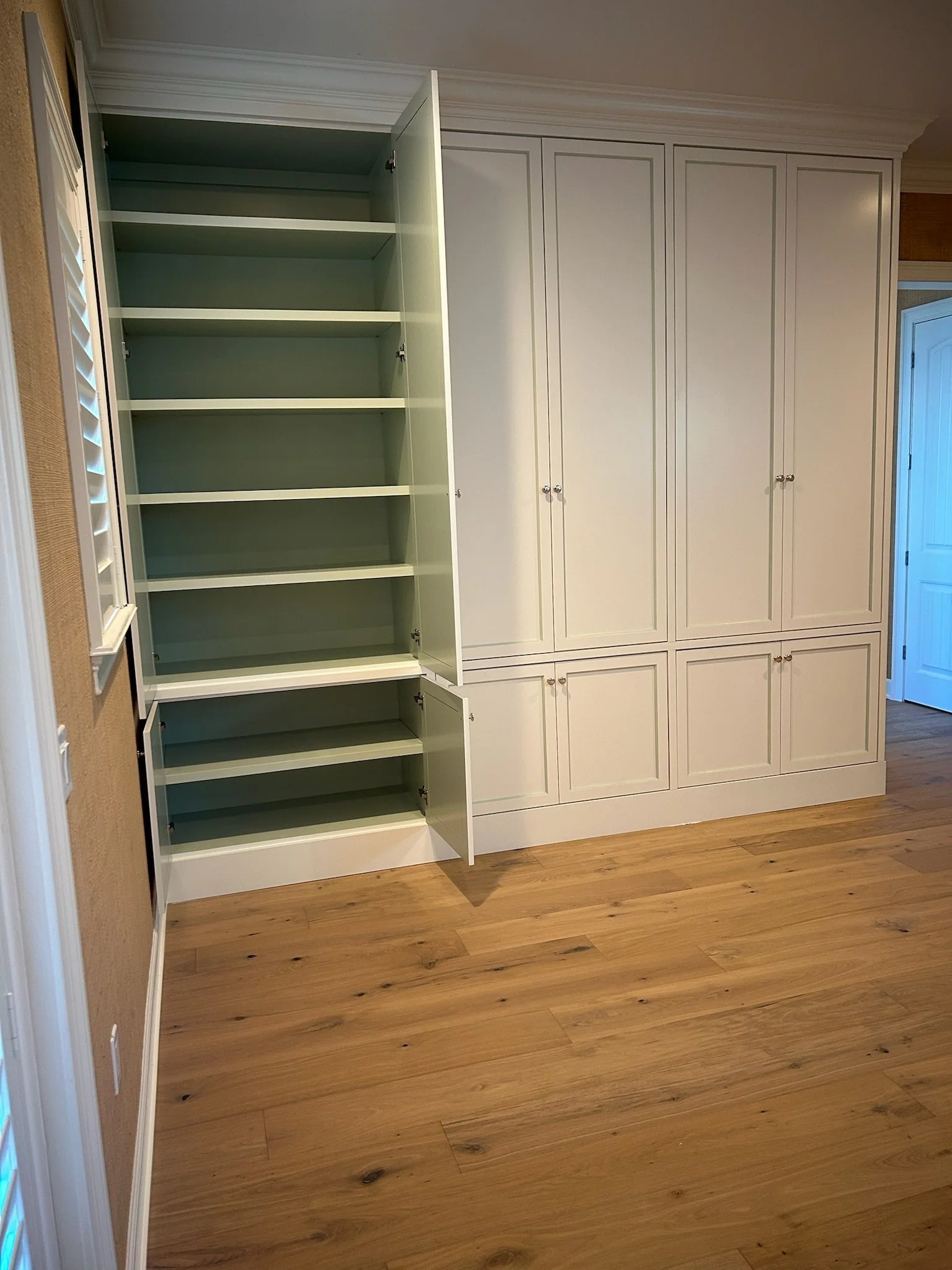 Empty built-in white custom cabinets with open shelves on a wooden floor.