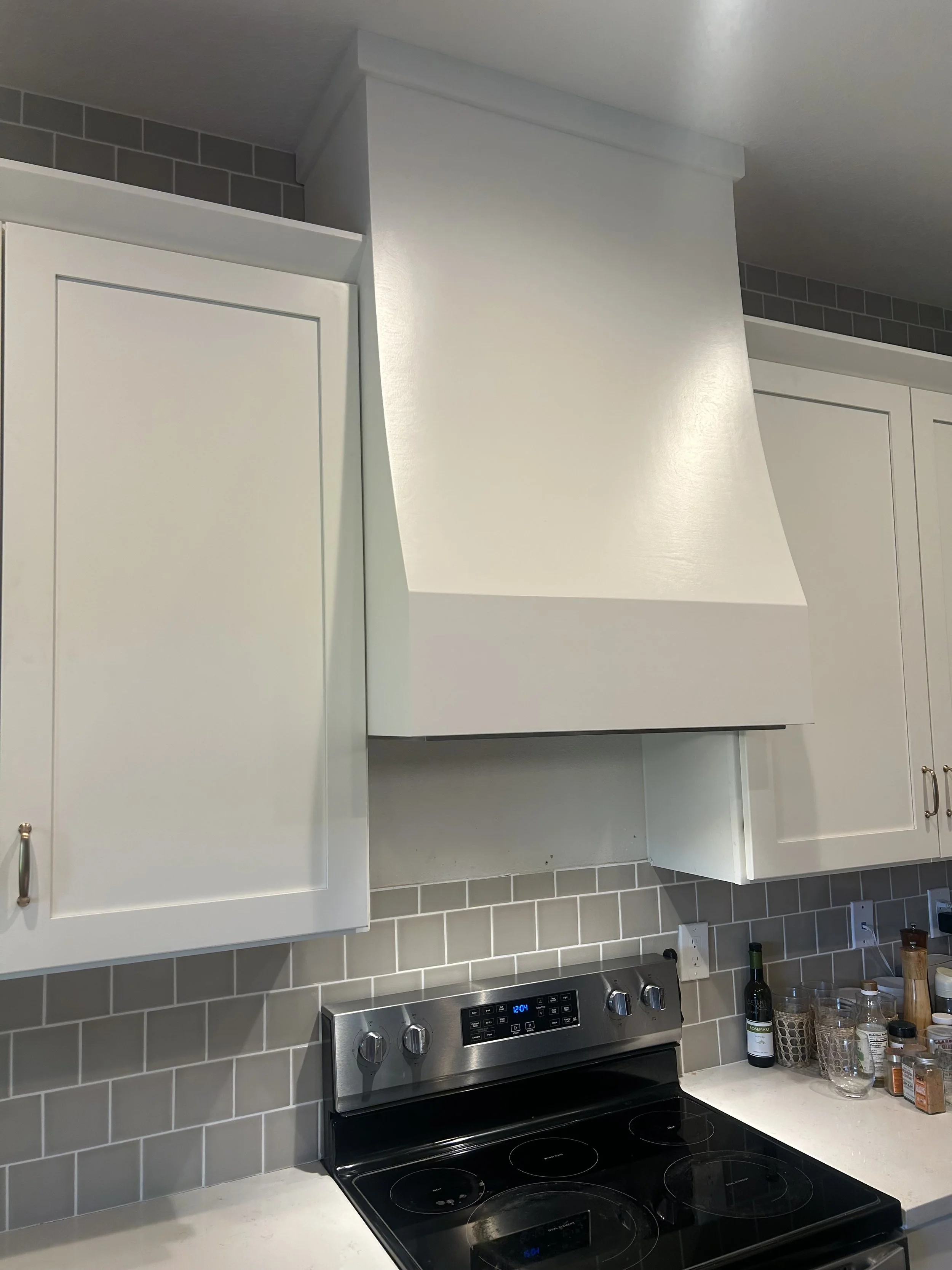 Kitchen with white custom cabinets and custom wood hood