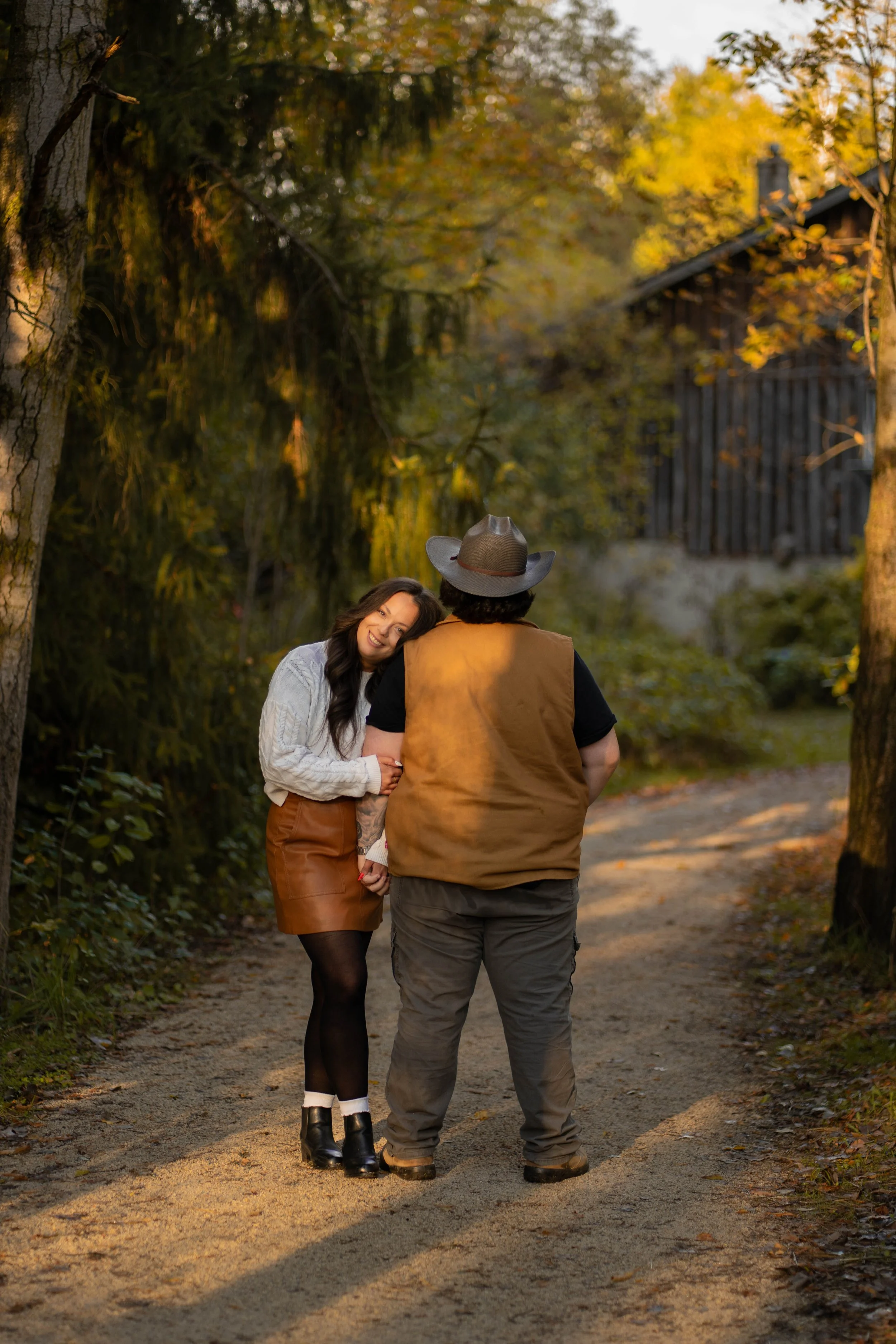 A couple sharing a joyful moment, leaning in close and smiling in a lush outdoor setting surrounded by greenery.