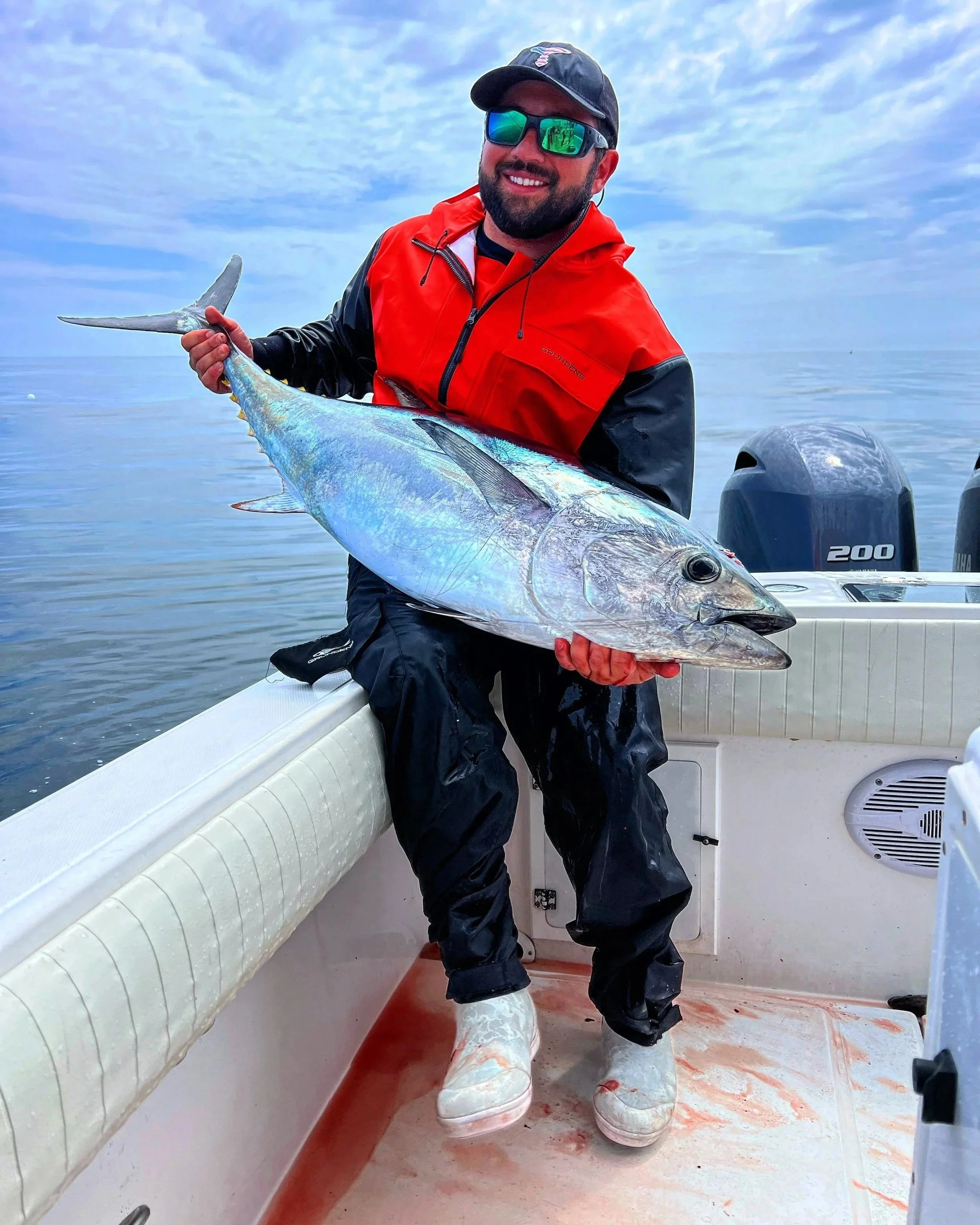 Modern wooden house in a mountainous landscape with a large glass window reflecting the sky and trees.