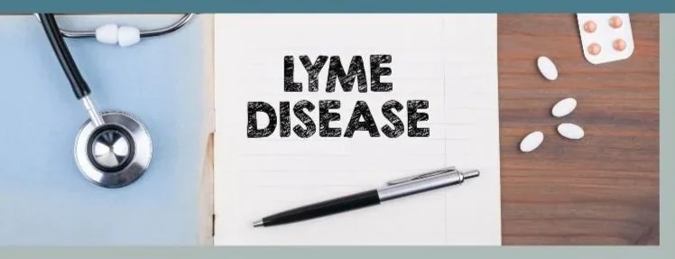 A stethoscope, a notebook with 'Lyme Disease' written on it, a pen, and pills on a wooden surface.