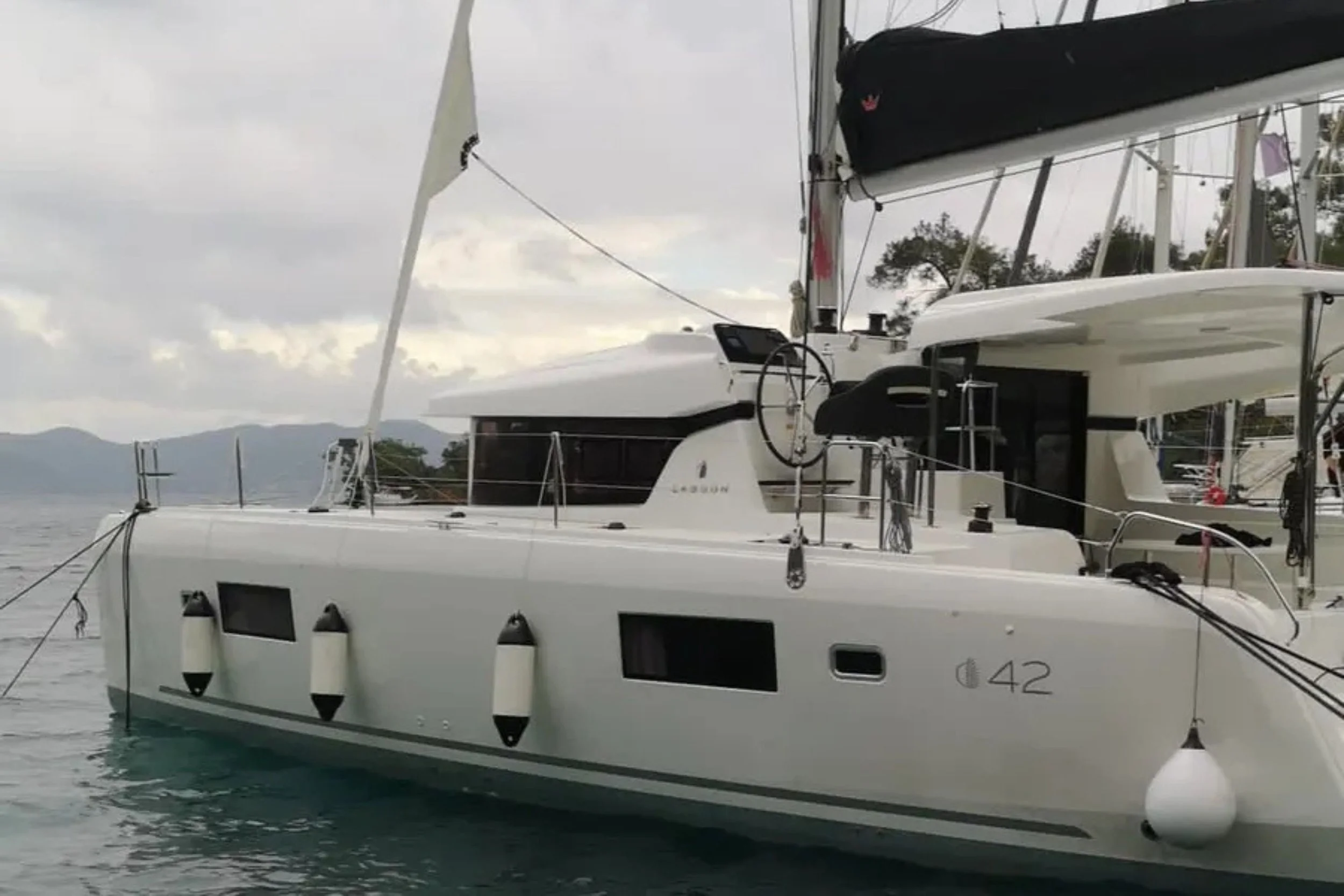 A white yacht on the water with a cloudy sky in the background.