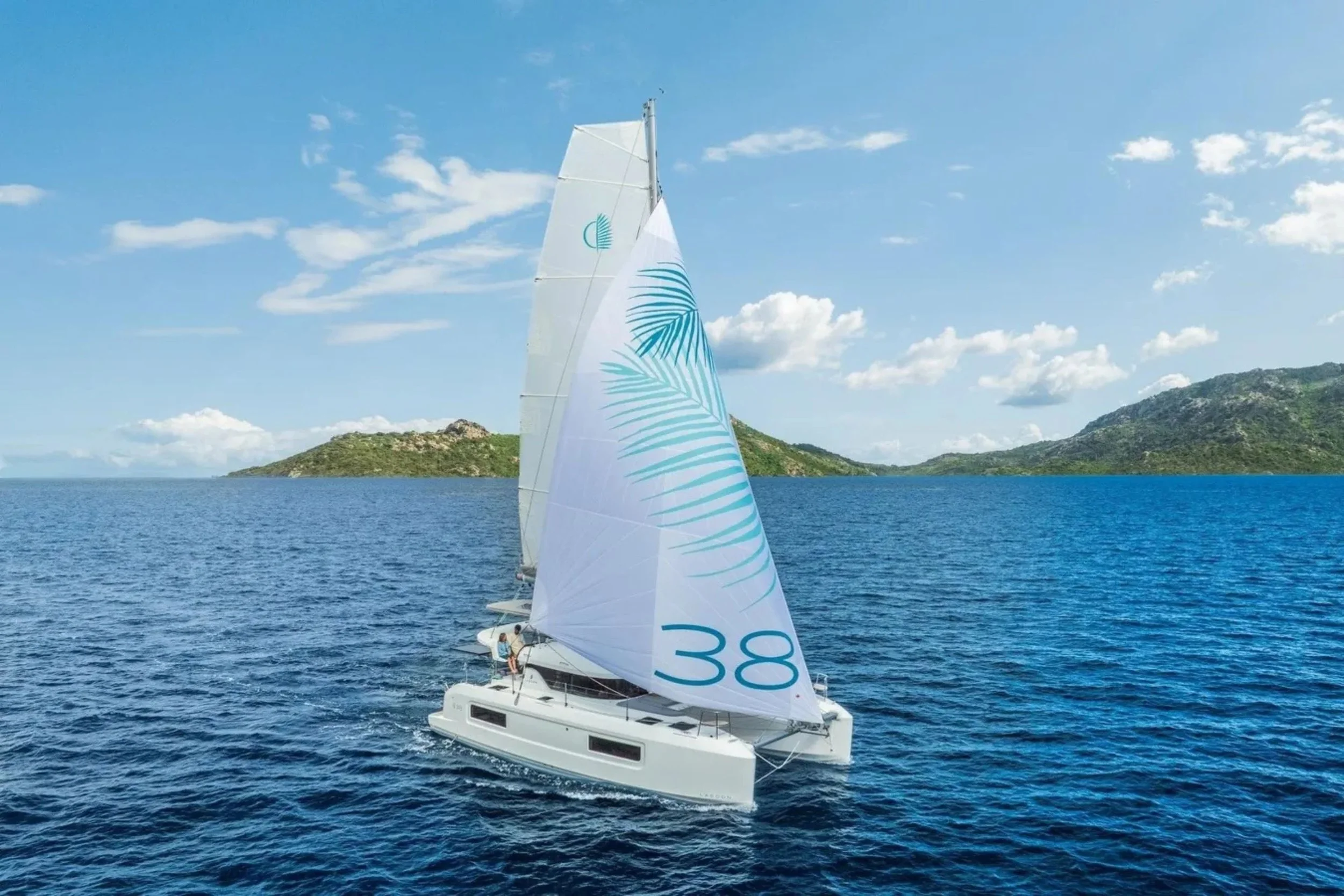 A sailboat with white sails numbered 38, sailing on blue ocean water near green islands under a partly cloudy sky.