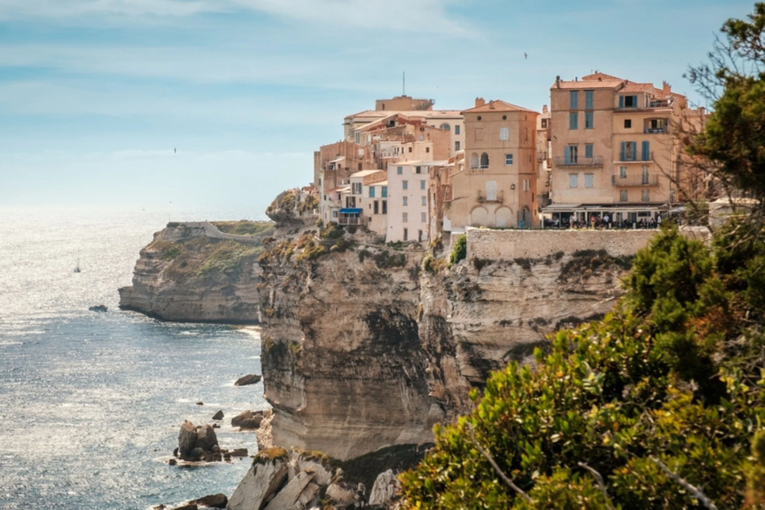 Cliffside houses overlooking the sea with clear blue sky.