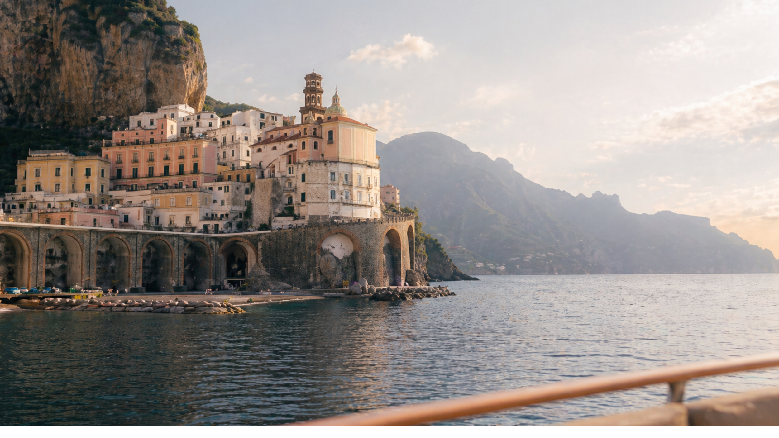 Quiet Amalfi Coast harbour and cliffside village seen from the water with soft Mediterranean light and calm sea