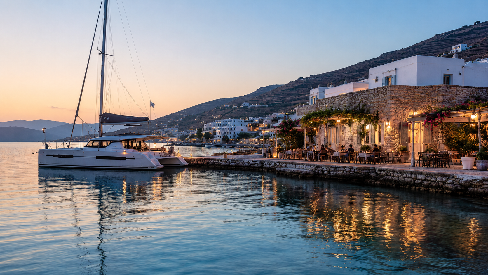 Modern catamaran at rest in a peaceful Greek island harbour with warm taverna lights ashore at sunset.