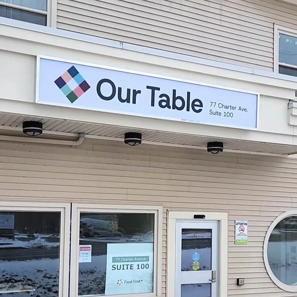 The Our Table building sign above the front door.