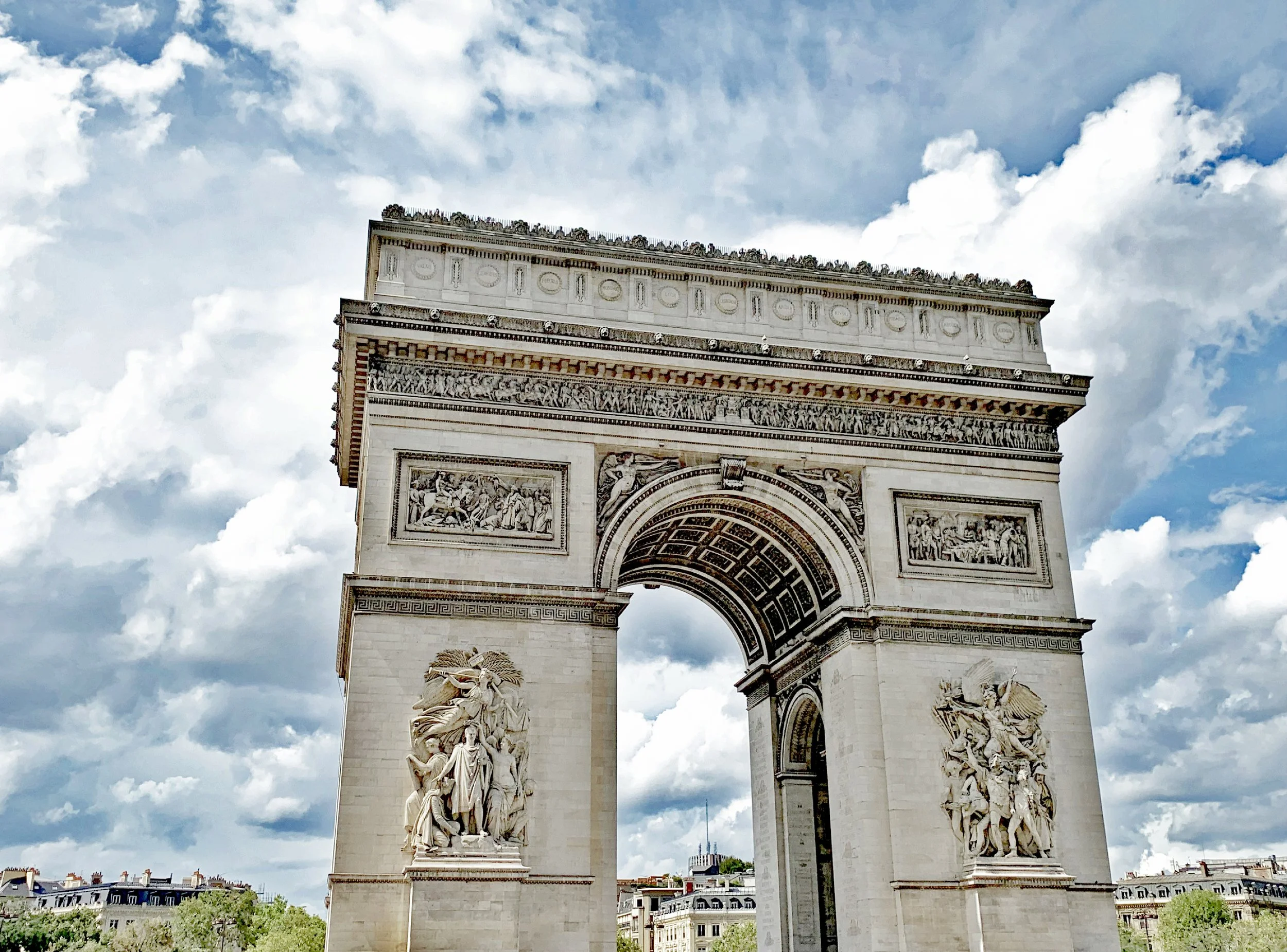 L'Arc de Triomphe de Paris vu de face, sous un ciel nuageux.