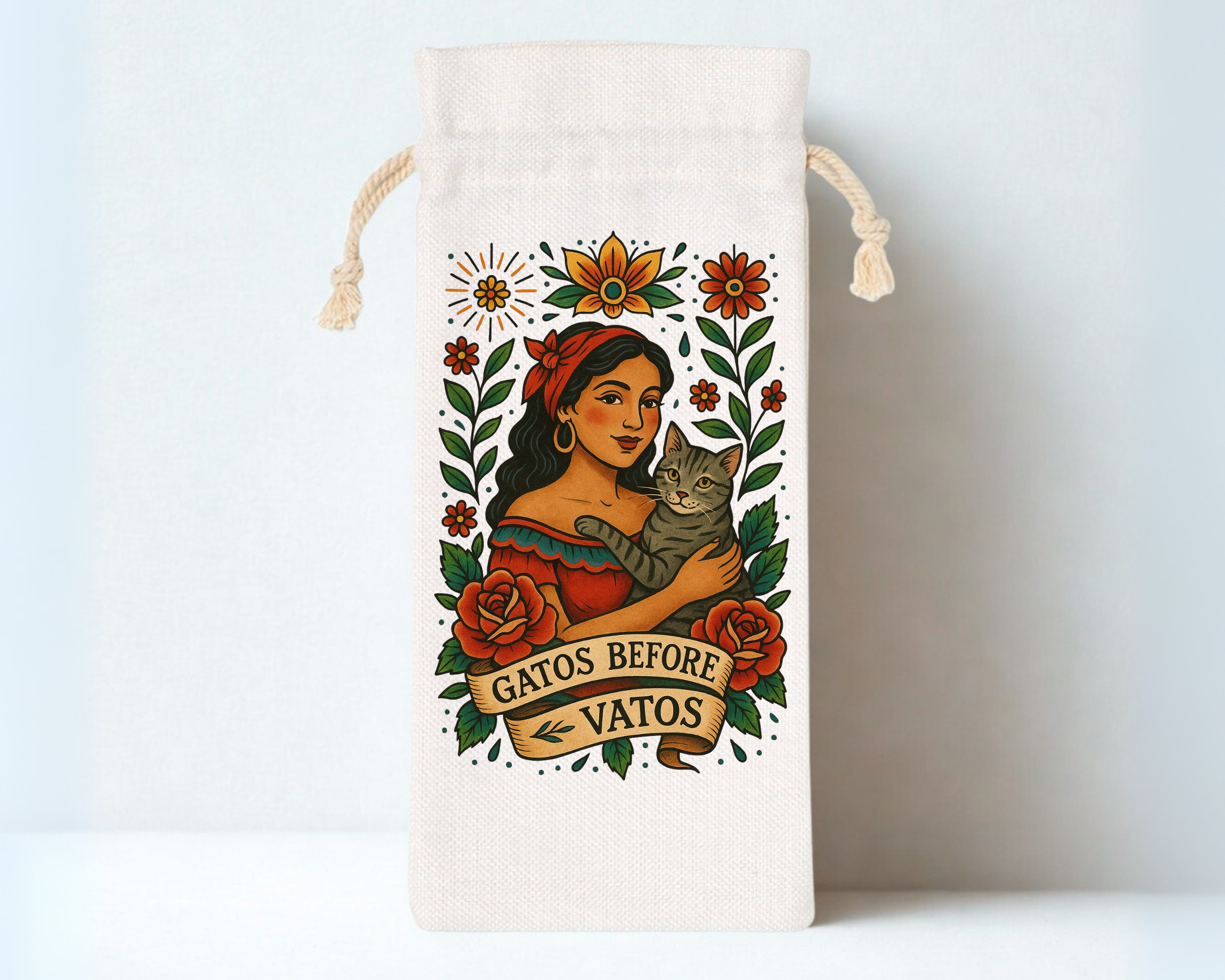 An illustration of a woman with dark hair, wearing a red headscarf and dress, holding a tabby cat, surrounded by colorful flowers and leaves, with a banner that reads "Gatos Before Vatos."