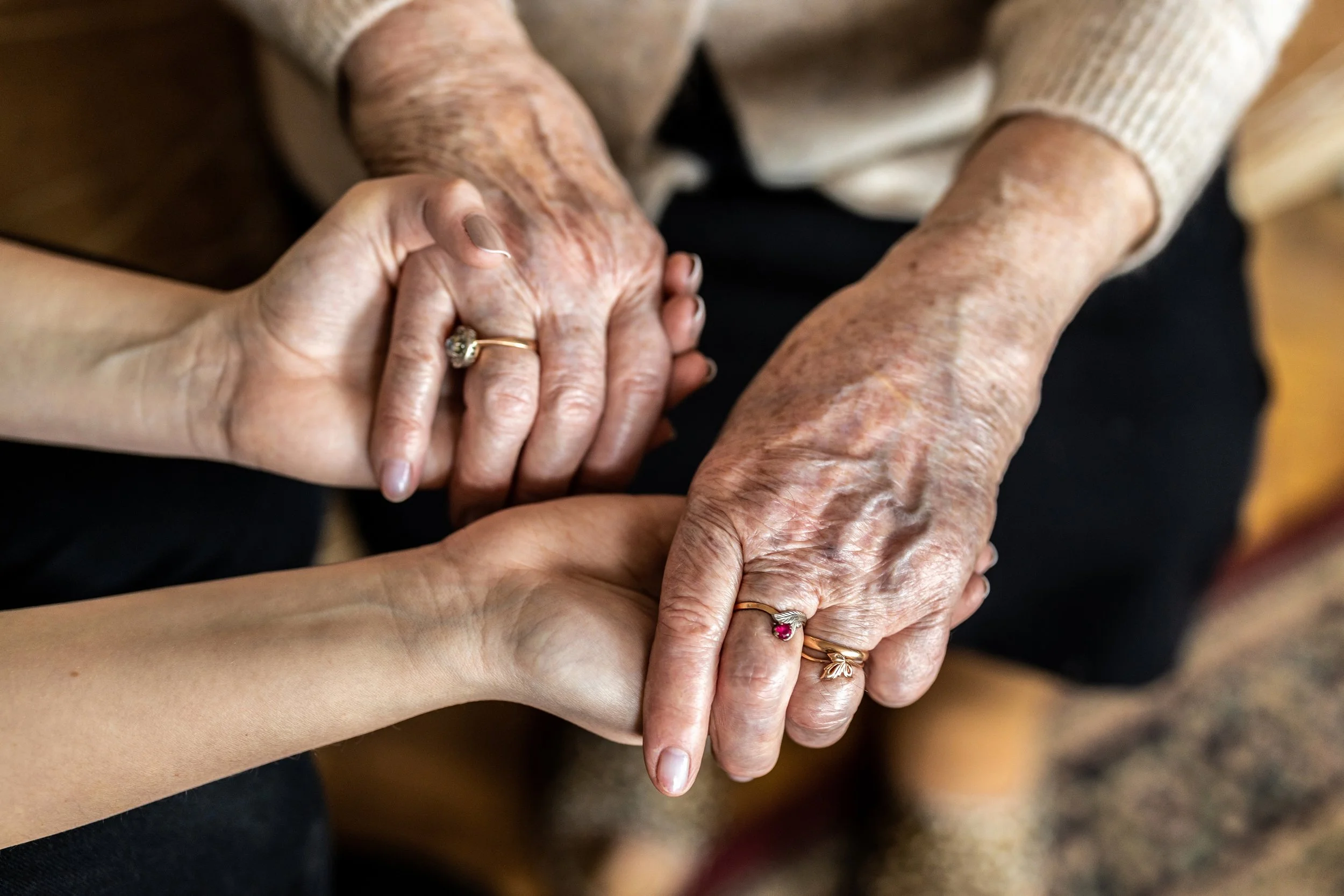 Multiple hands, including elderly and young, holding each other, symbolizing care and connection.