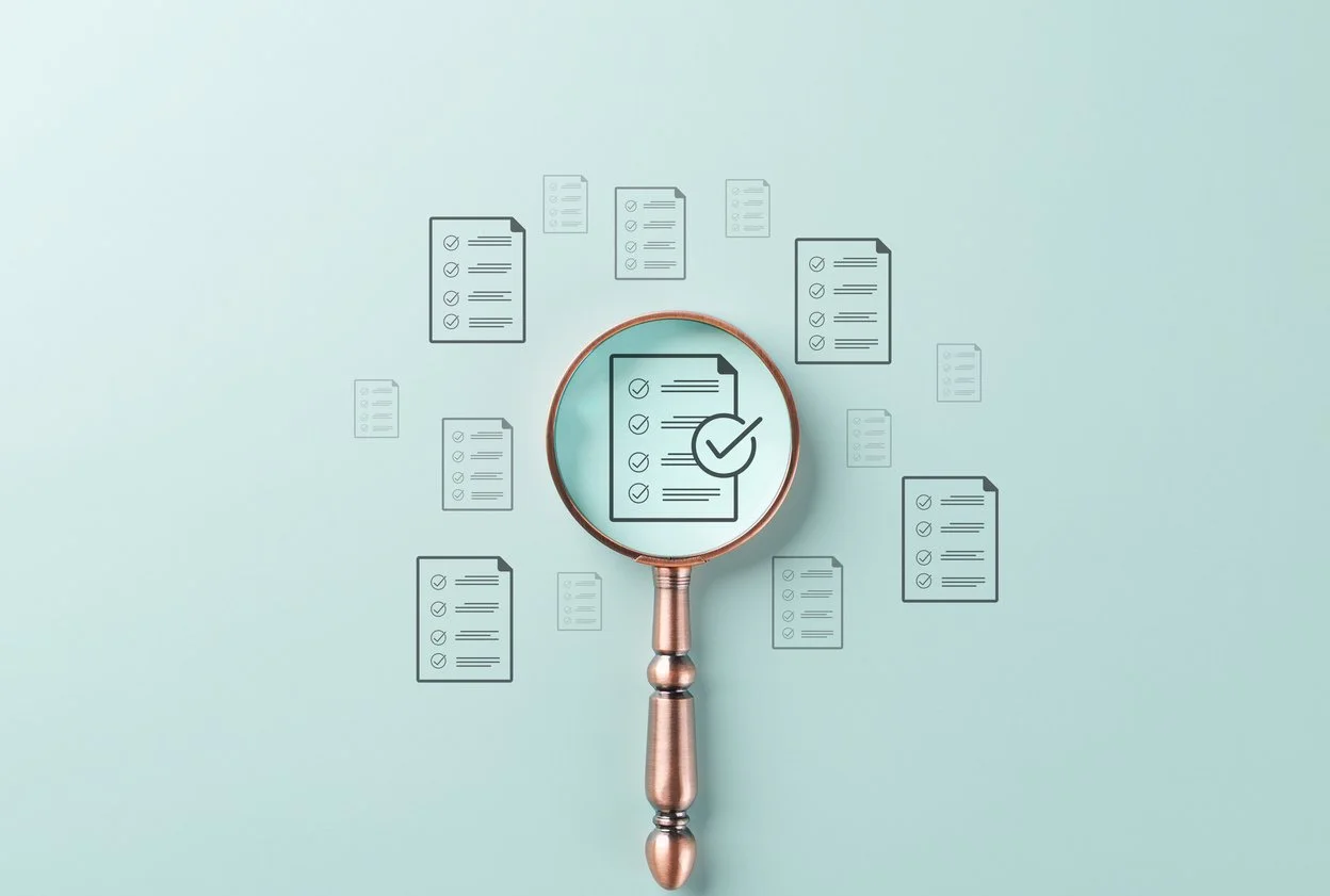 A magnifying glass over checklist document, symbolizing quality control, document review, auditing, compliance, and business process verification