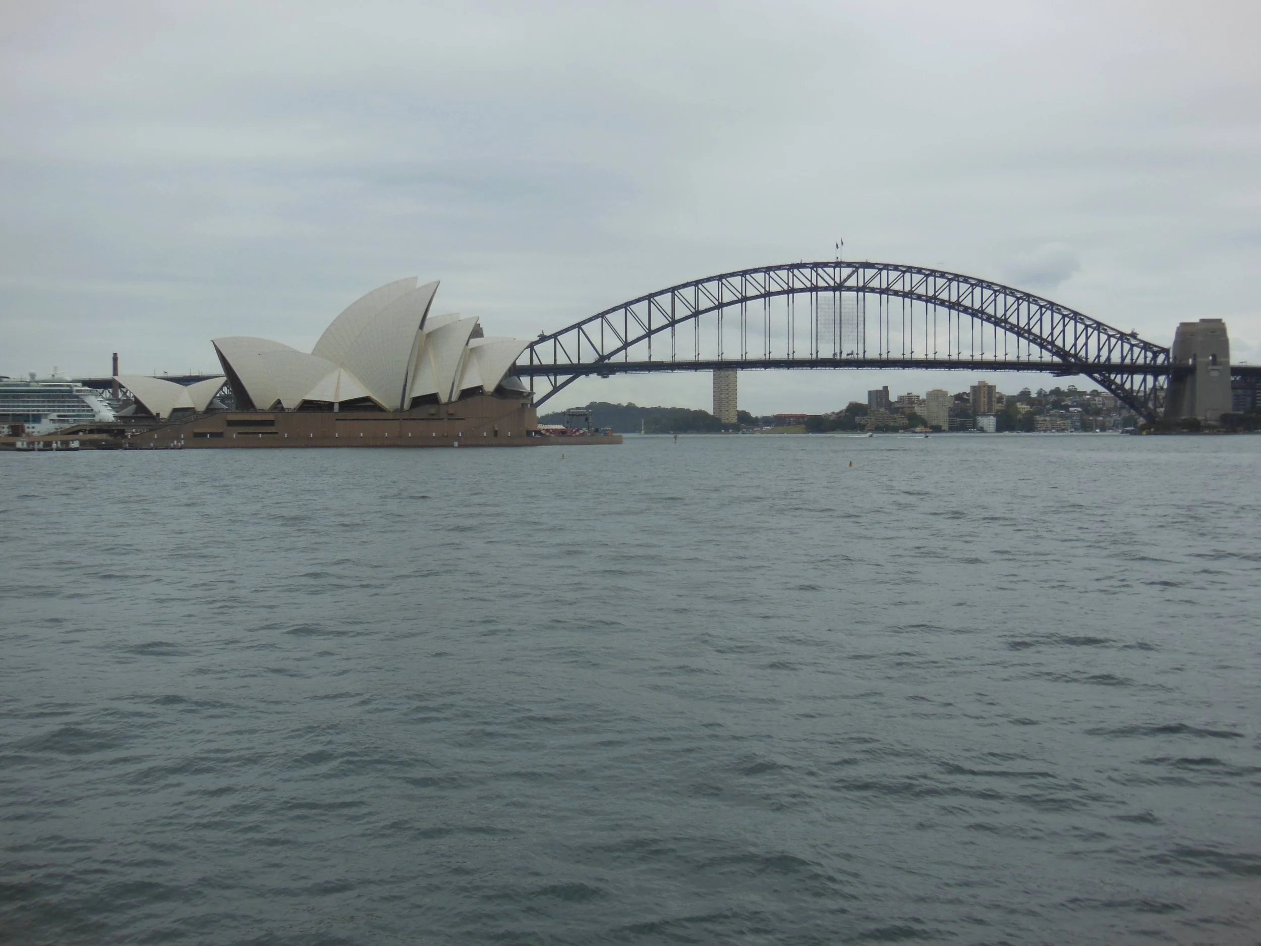 View of the Sydney Opera House and Harbour Bridge in Sydney, Australia, on a cloudy day.