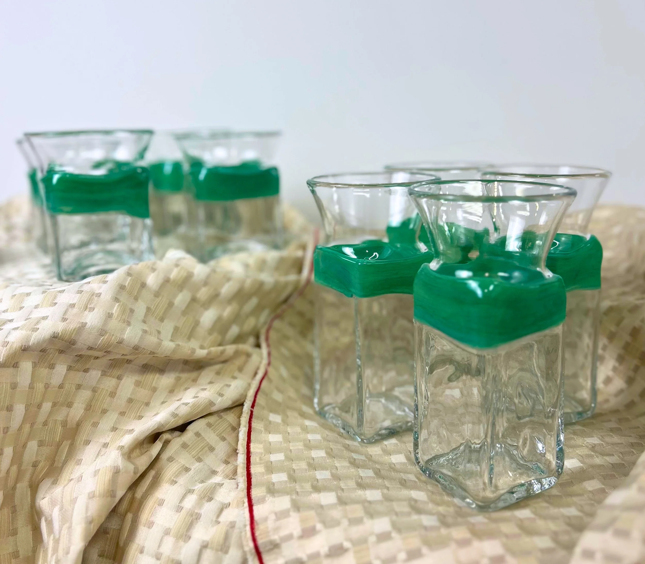 Set of empty glass jars with green rubber seals, arranged on a beige textured cloth.