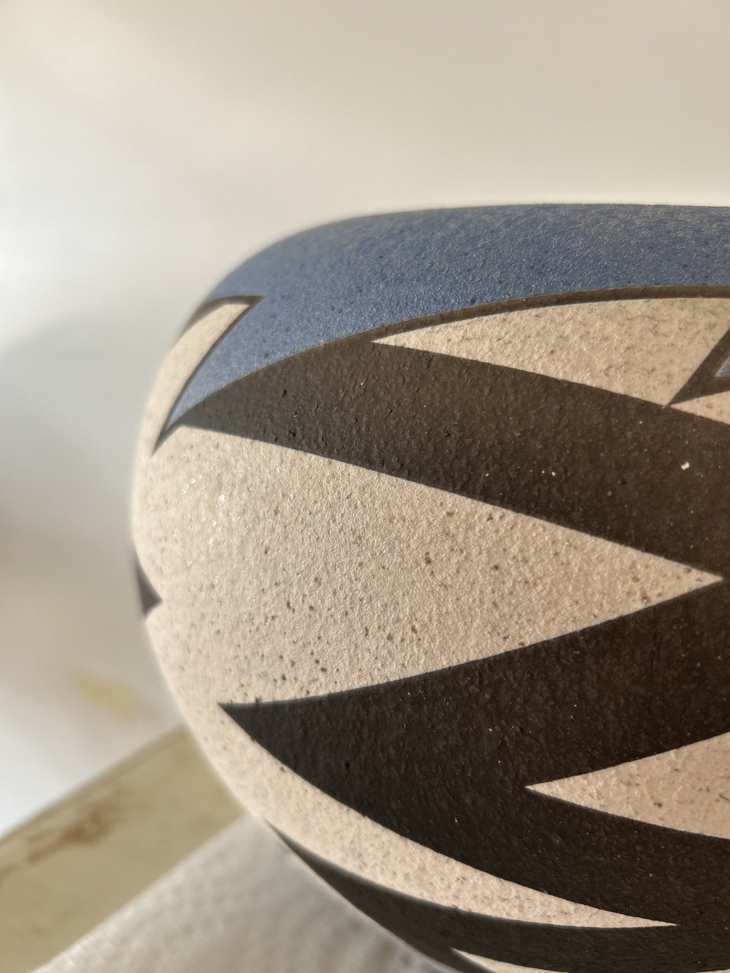 Close-up of a spherical decorative object with abstract black, beige, and blue geometric patterns.