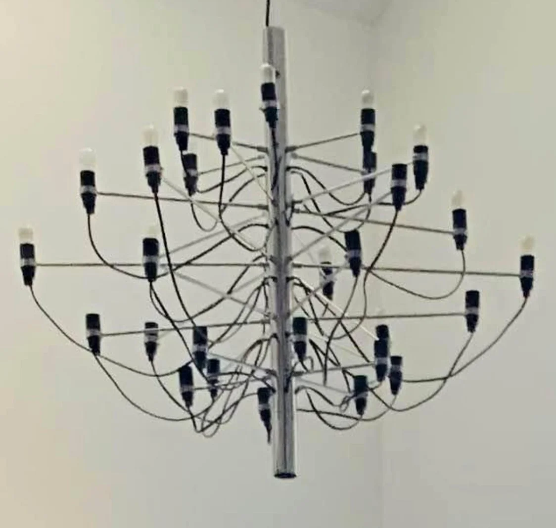 Chandelier with multiple black and white light sockets and wires, hanging from ceiling.