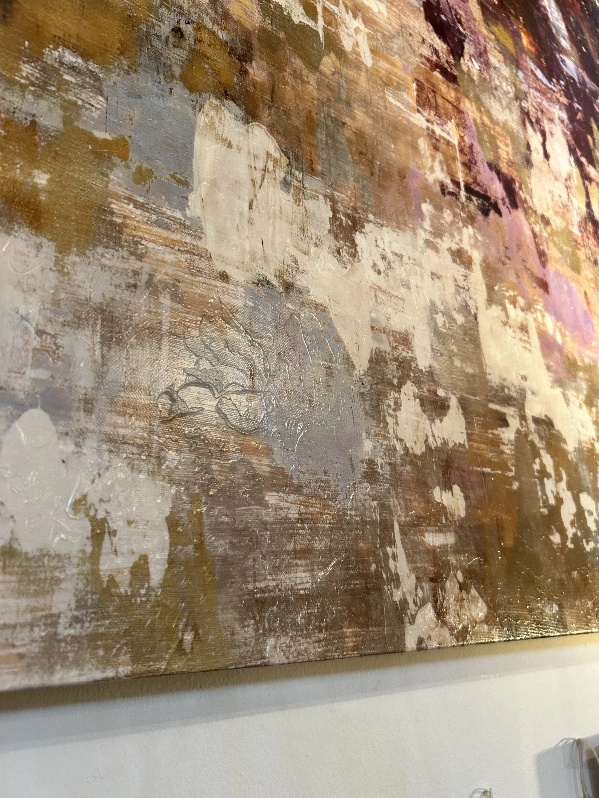 Close-up of an abstract textured painting with earth tones and patches of purple and pink.