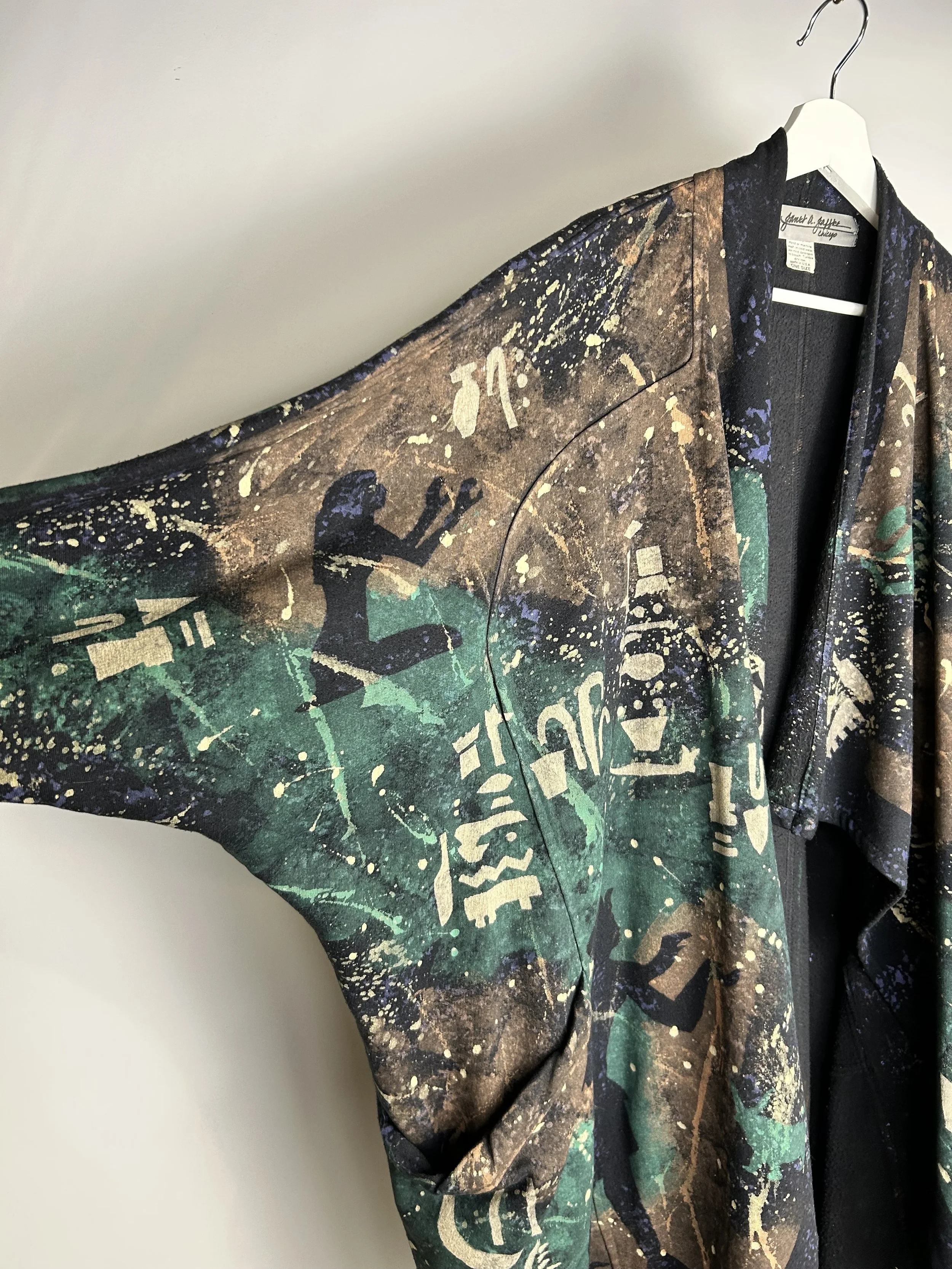 A colorful jacket with a print of a woman jogging and various abstract graphics hanging on a white hanger.