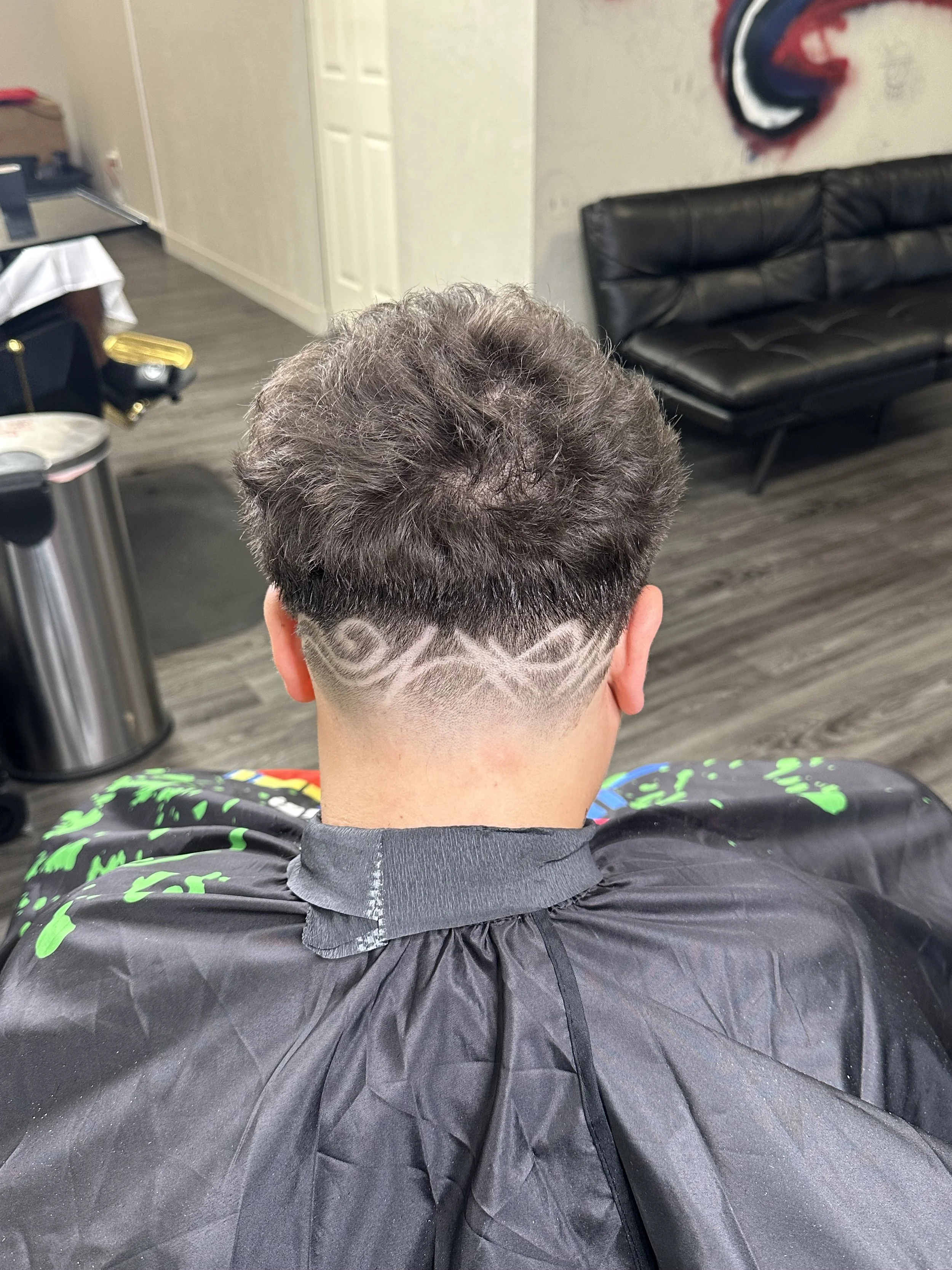 A person with a fresh haircut featuring intricate geometric designs shaved into the lower part of their hair.