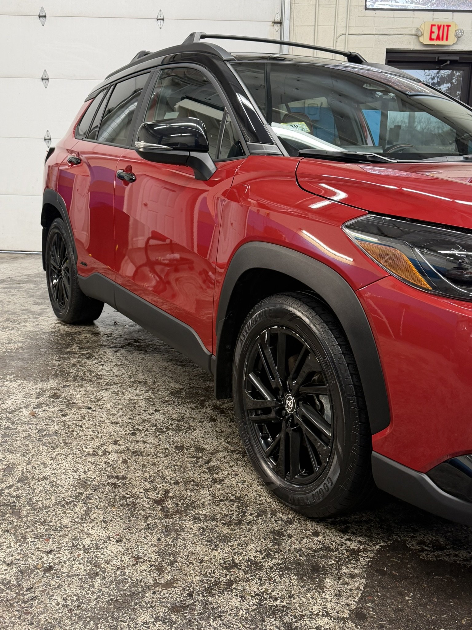 Red compact SUV with black rims and black trim parked inside a garage.