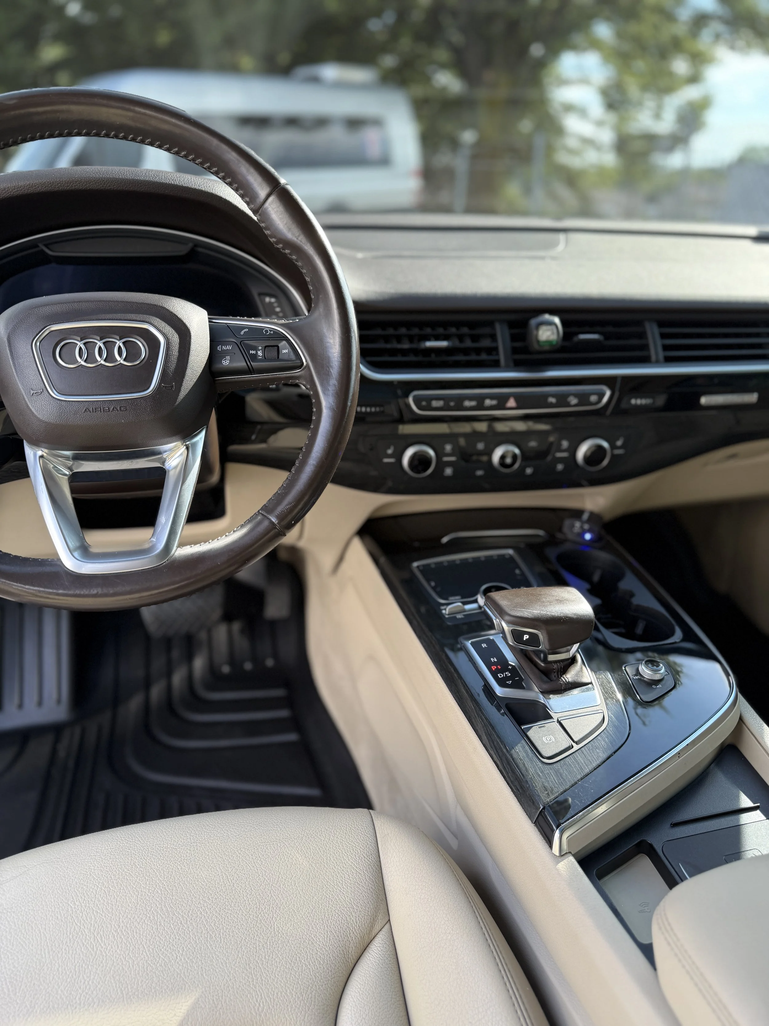 Interior of an Audi car, showing steering wheel, center console with gear shifter, and dashboard with air conditioning controls.
