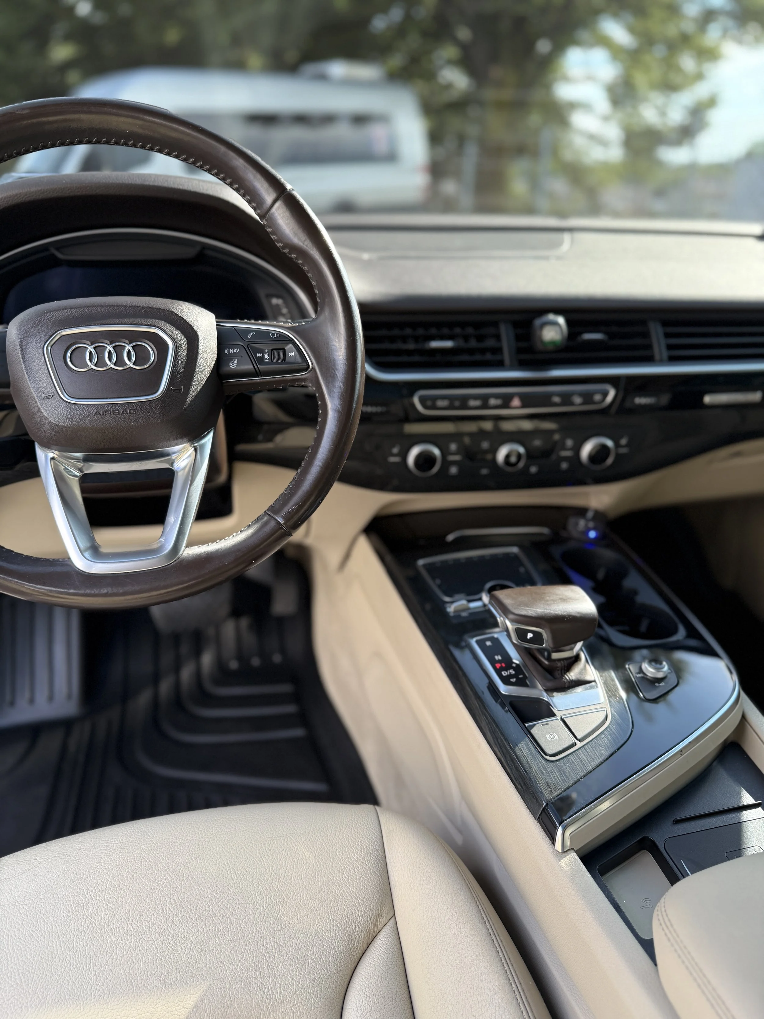 Interior of an Audi car showing the steering wheel, gear shift, dashboard, and center console.