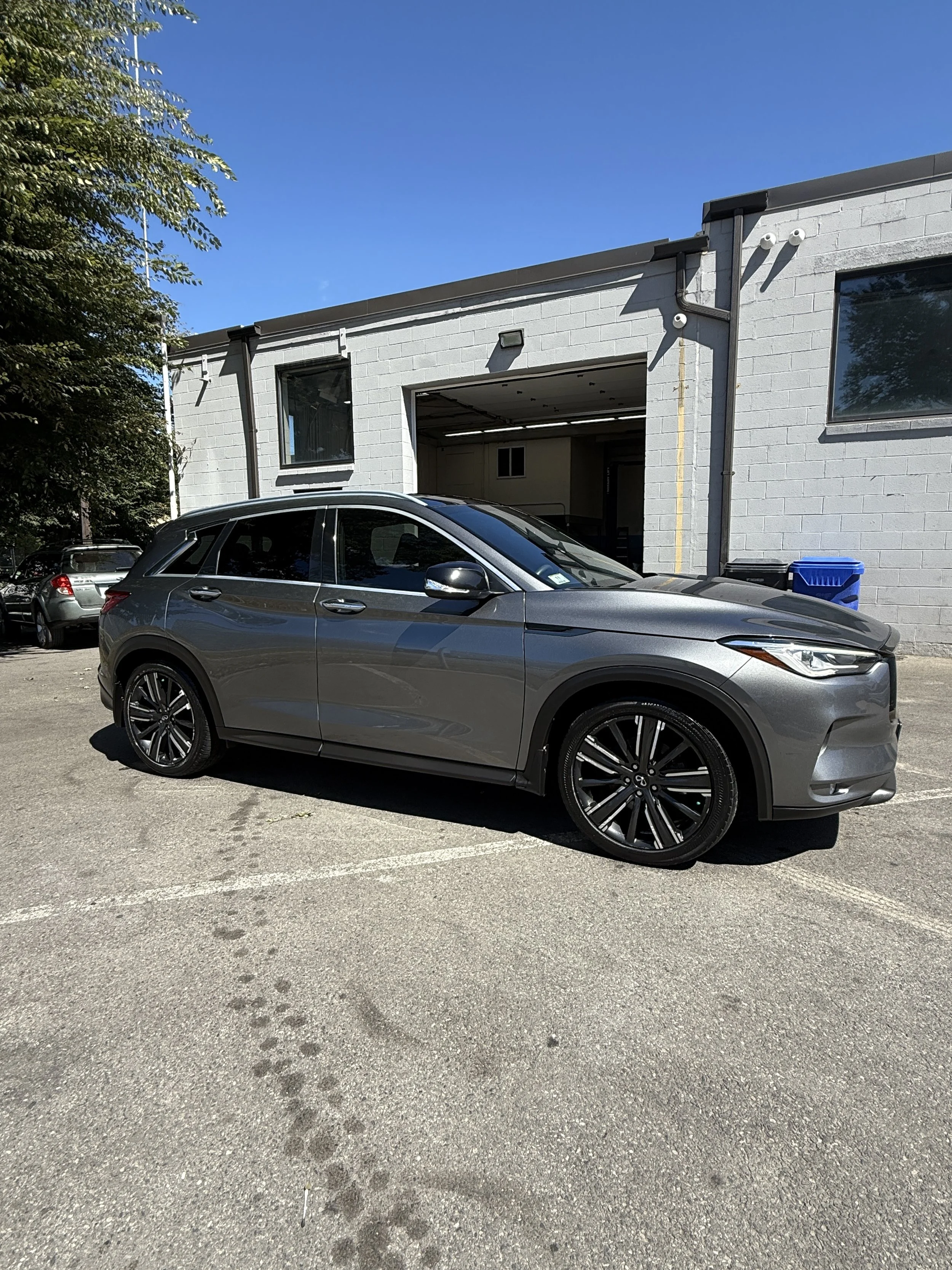 Gray SUV car parked in a parking lot outside a gray building under a clear blue sky.