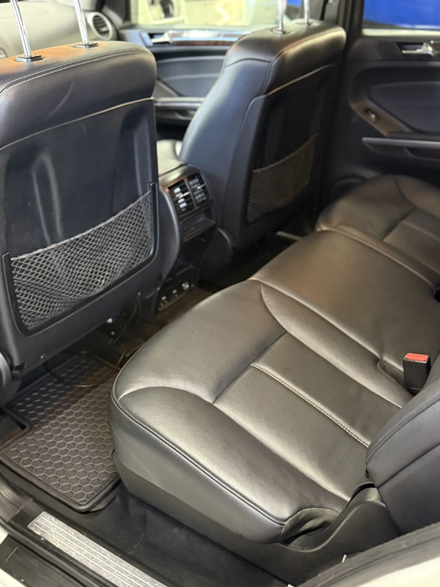 Backseat interior of a car with black leather seats, seatbacks, and rear air vents.