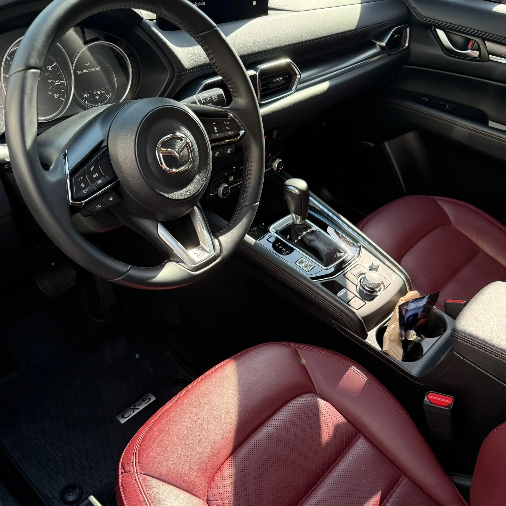 Interior of a Mazda CX-5 with red leather seats, steering wheel, gear shifter, and central controls.