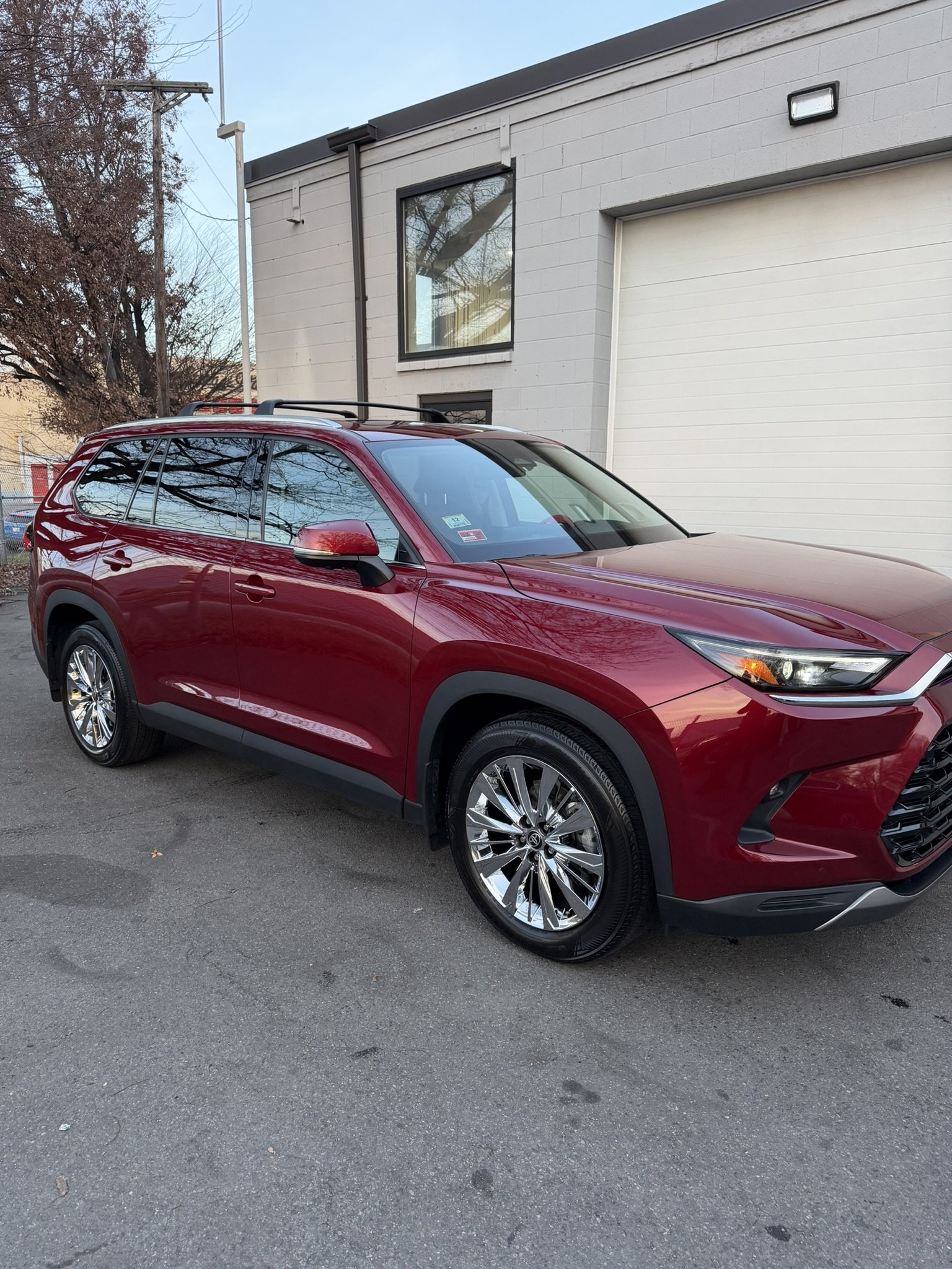 Red SUV parked in front of a modern building with white exterior walls.