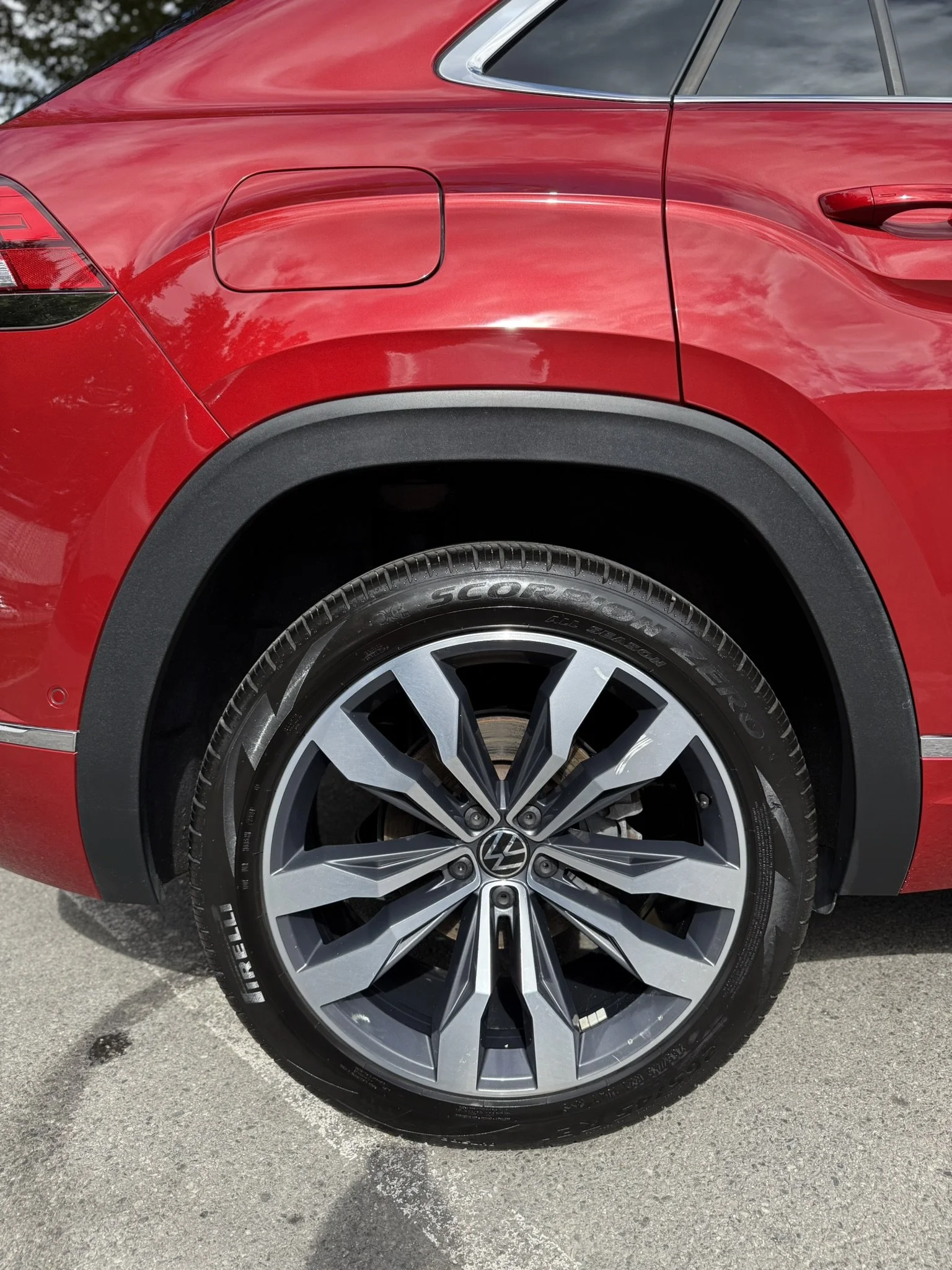 Close-up of a red Volkswagen vehicle's rear wheel and fender, showing the alloy rim and tire.