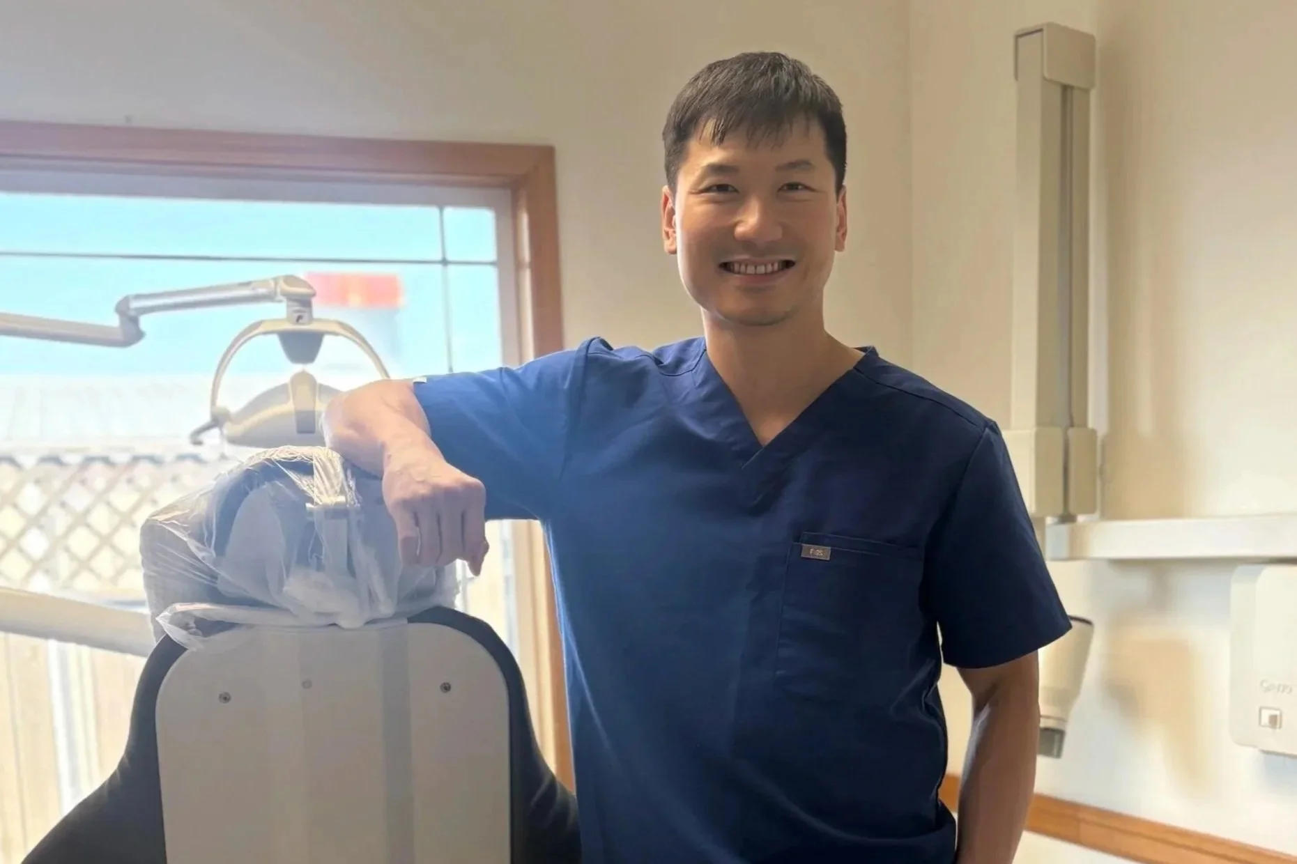 Friendly family dentist in Centralia, WA, standing by dental equipment in a bright, modern operatory at Twin City Smiles.