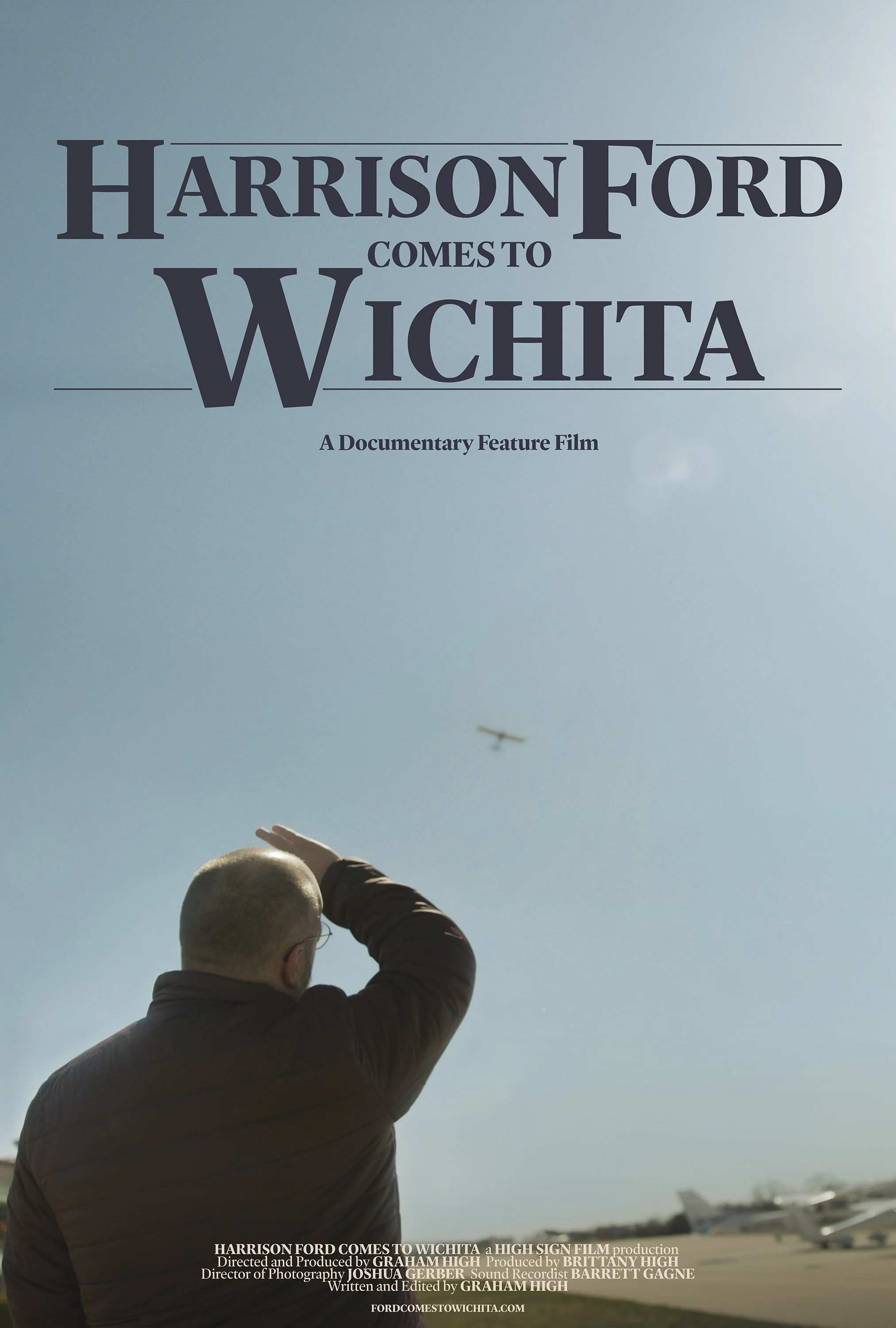 Man shields his eyes while looking up at a plane flying through the sky
