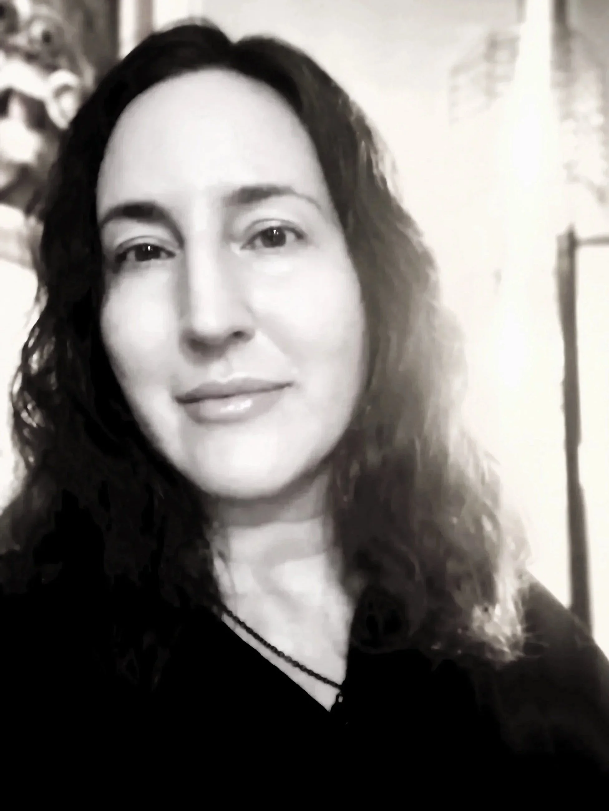 Black and white portrait of Lorelei Ark, a woman with long wavy hair and a gentle expression, symbolizing calm presence and depth.