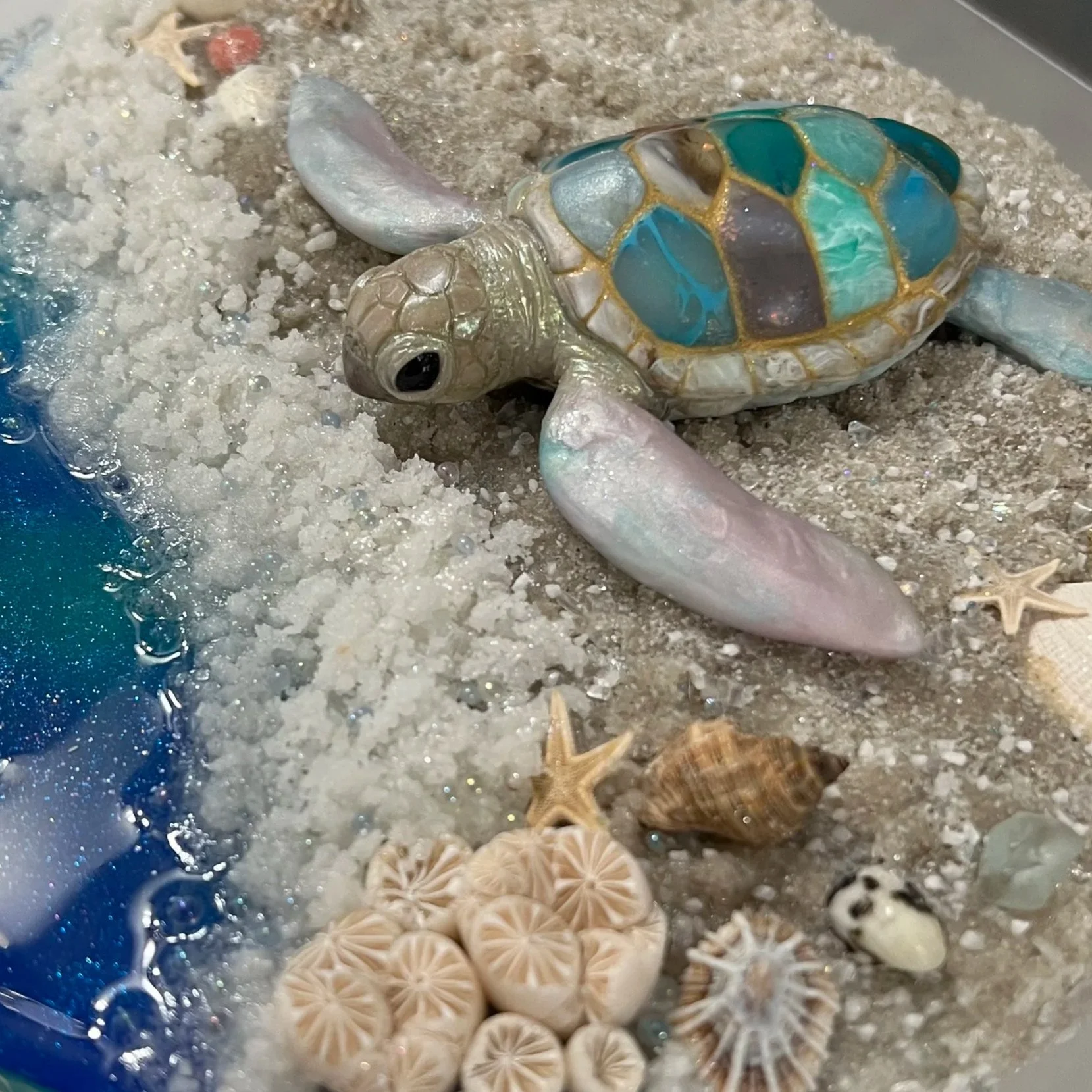 Baby Sea turtle sculpture with opal fins and faux stone shell, placed on a sparkling sand beach/available to buy at Christina Brilla creations