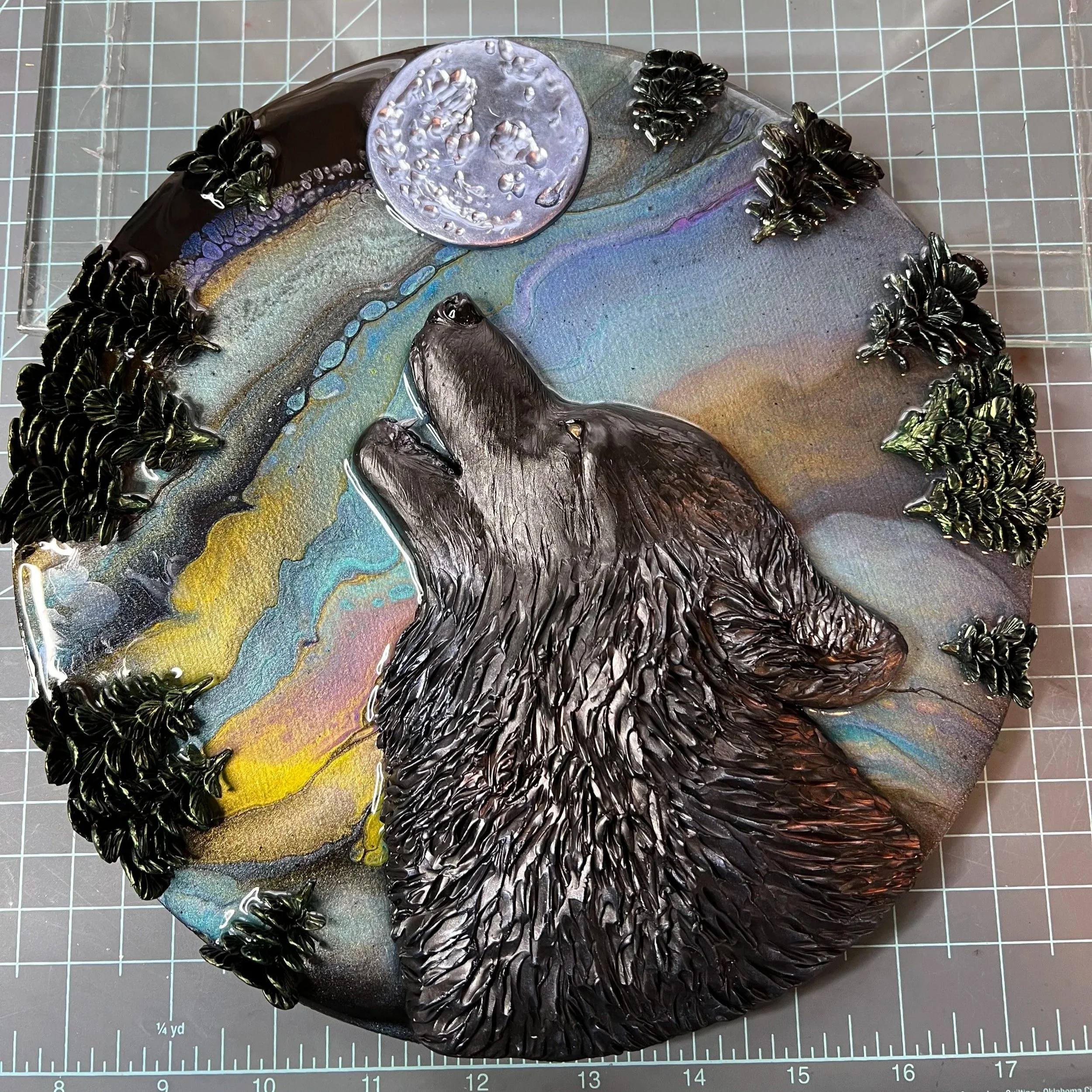 Colorful resin art with a black wolf howling, surrounded by black trees, and a shimmering moon in the sky.
