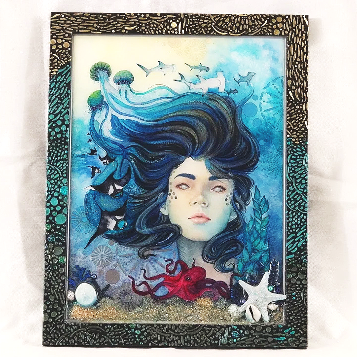 A framed watercolor artwork of a woman underwater with flowing blue hair, surrounded by marine life such as fish, octopus, starfish, and seashells, with an abstract aquatic background.