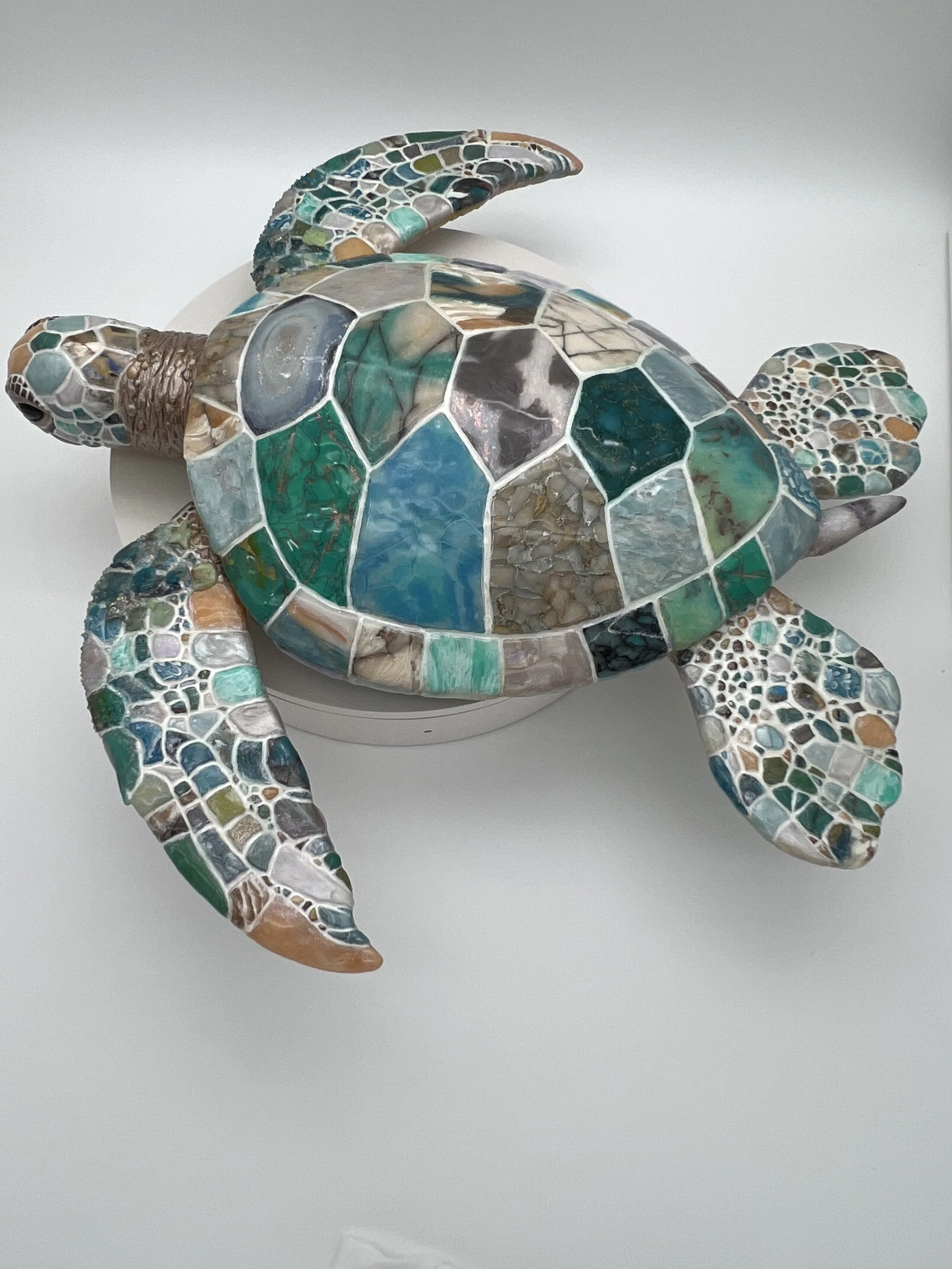 A mosaic sculpture of a sea turtle made with various colored pieces of tile and glass.