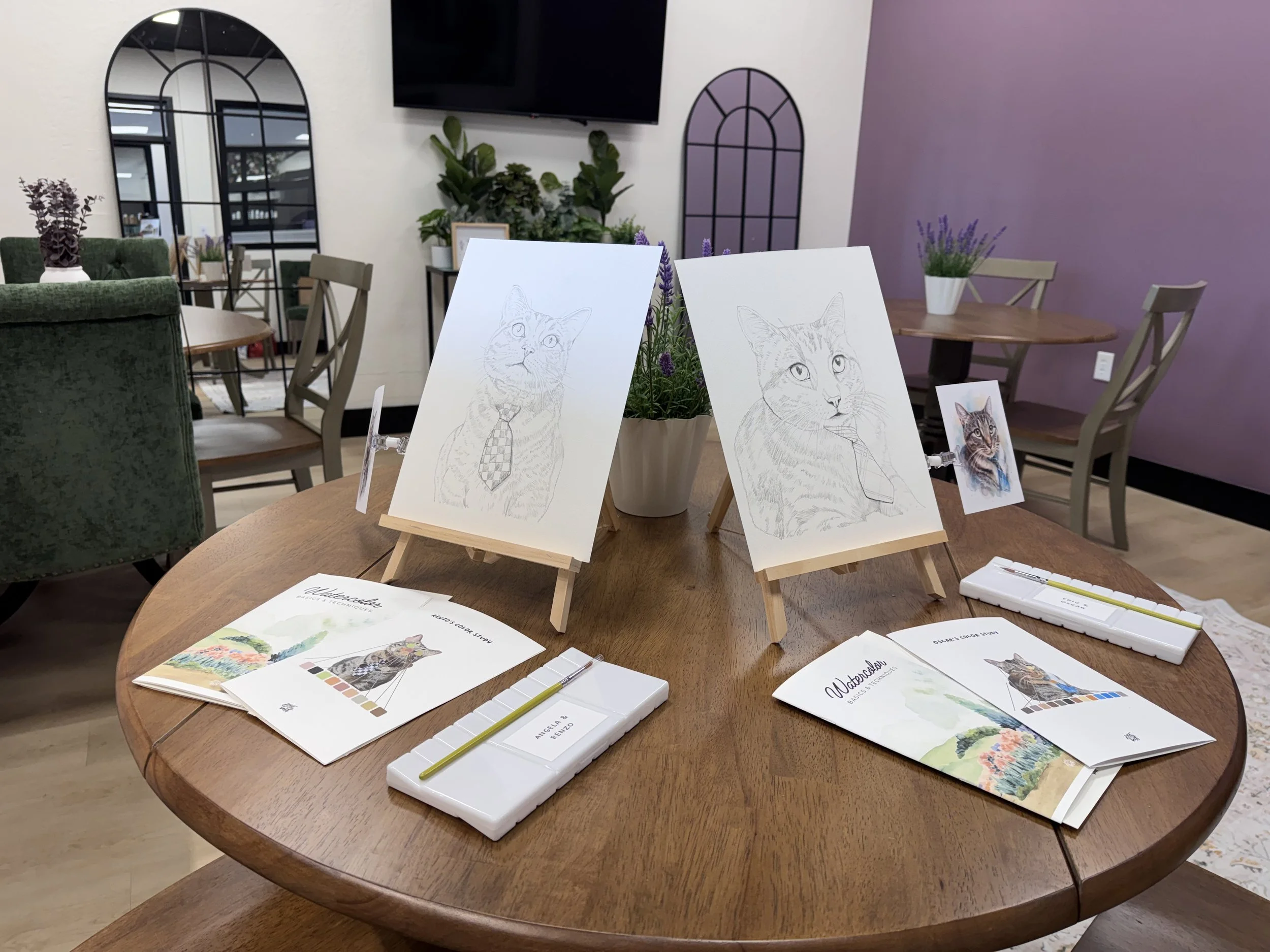 Watercolor pet portrait workshop setup at Tinc in College Park, Orlando, with pre-sketched cat portraits, watercolor palettes, and painting supplies.