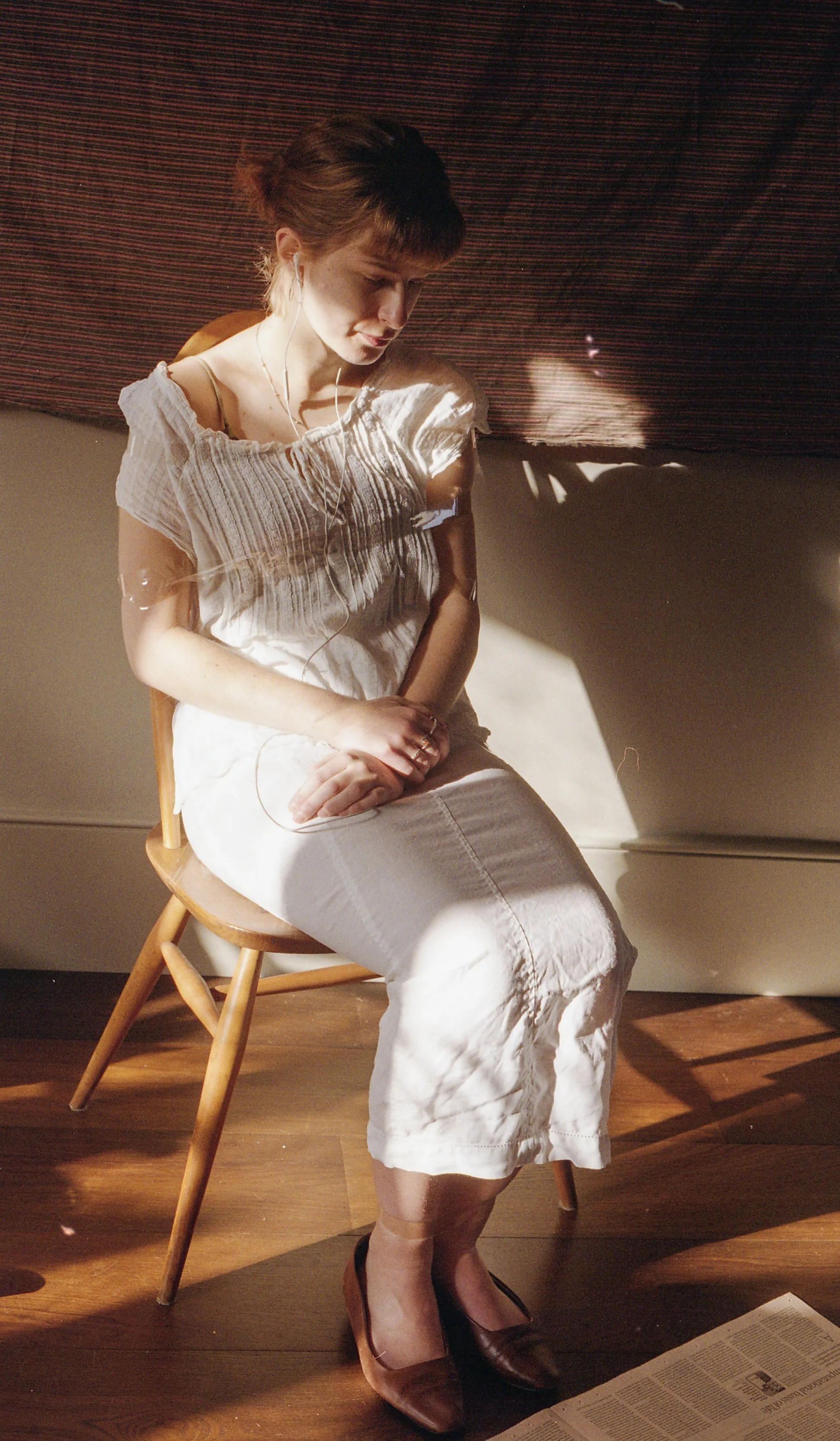 Contemporary fashion portrait photographed on analogue film, featuring natural light and sculptural greenery.