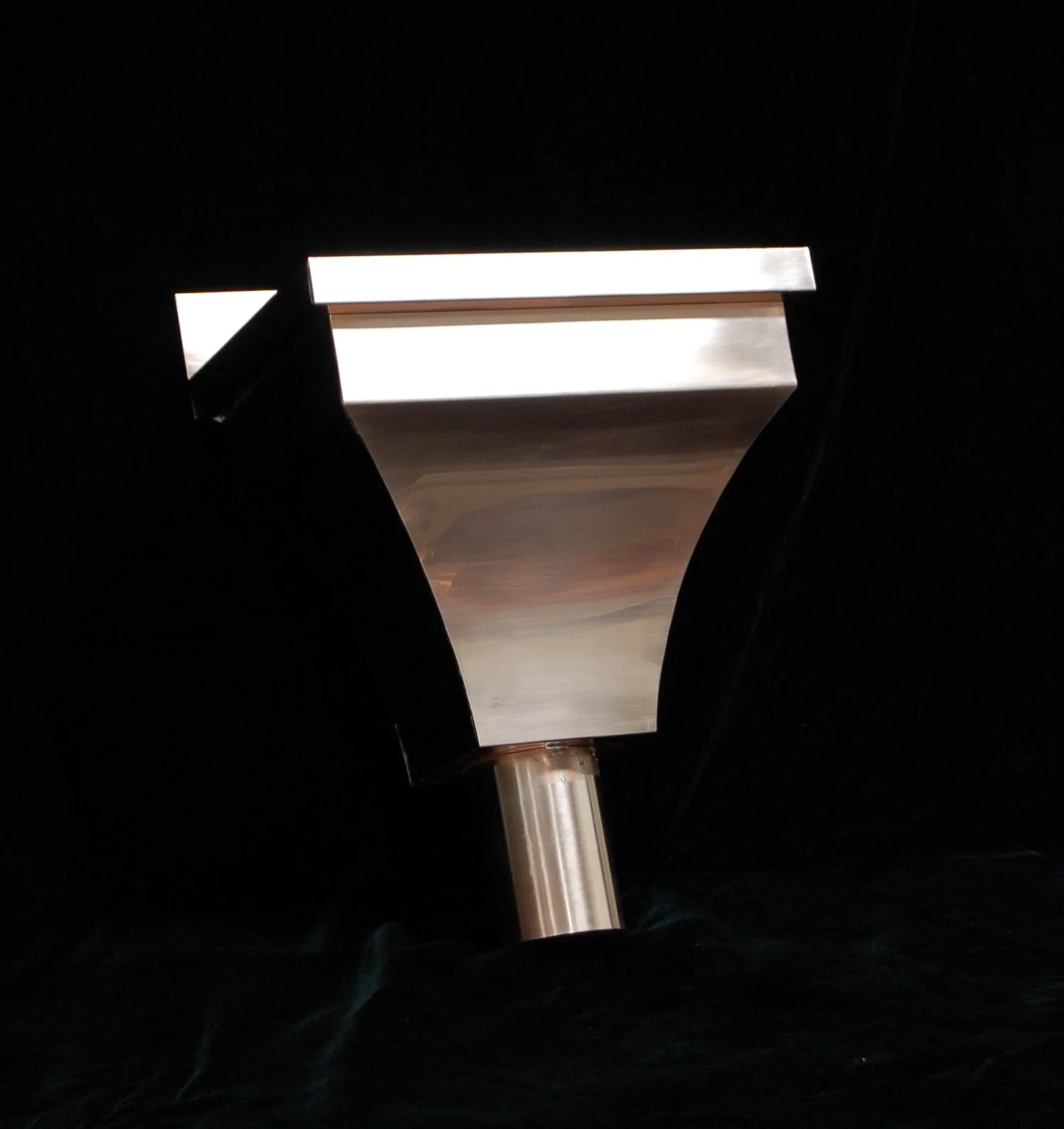 Close-up of a metallic object with a T-shaped top, set against a black background.