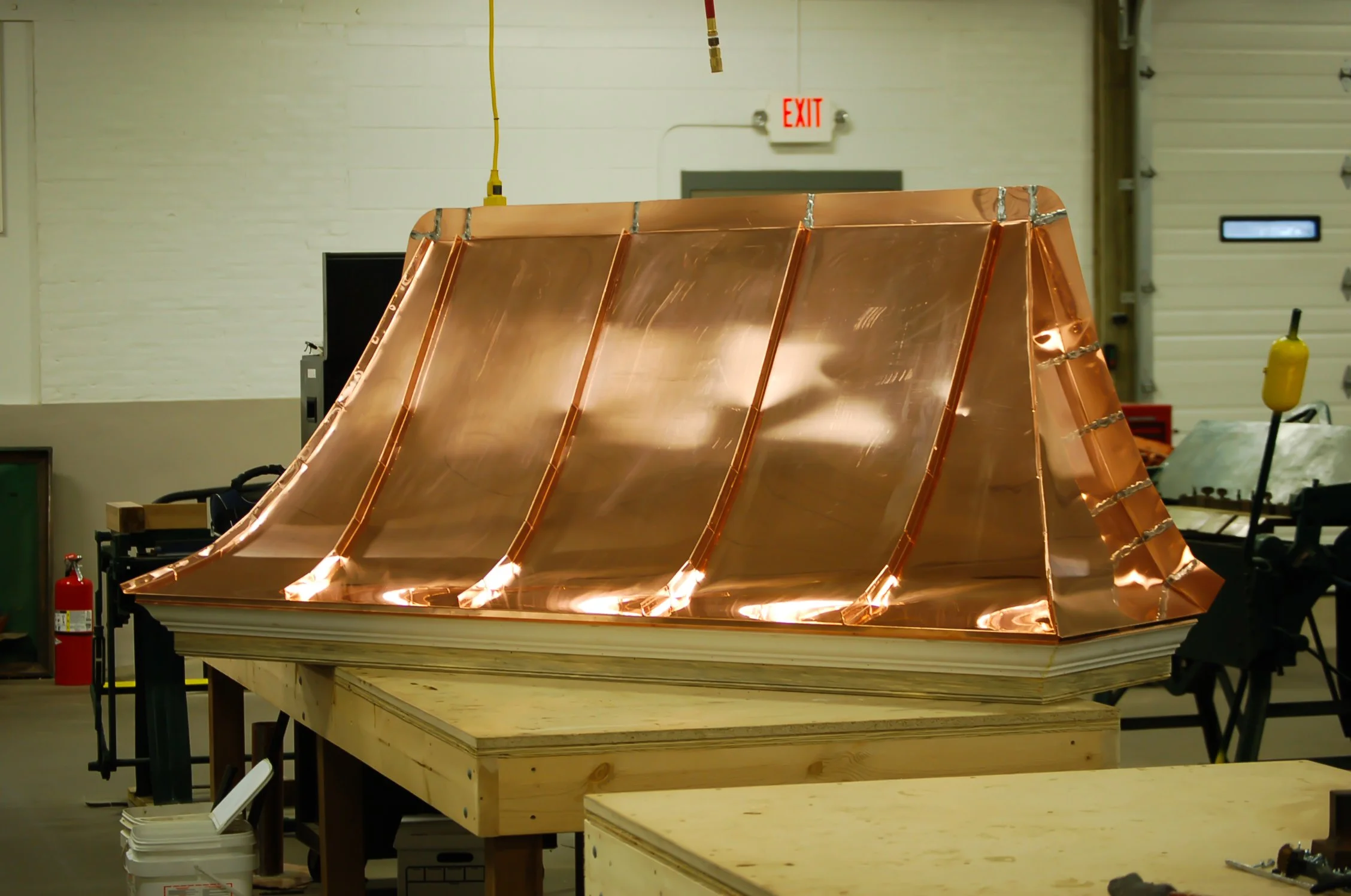 A copper dome structure with support ribs, placed on a wooden workbench in a workshop.