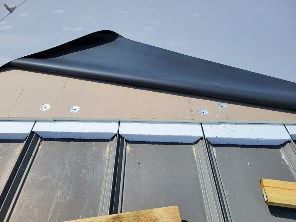 Close-up of roof panels with partially installed flashing and foam blocks for insulation or leveling.