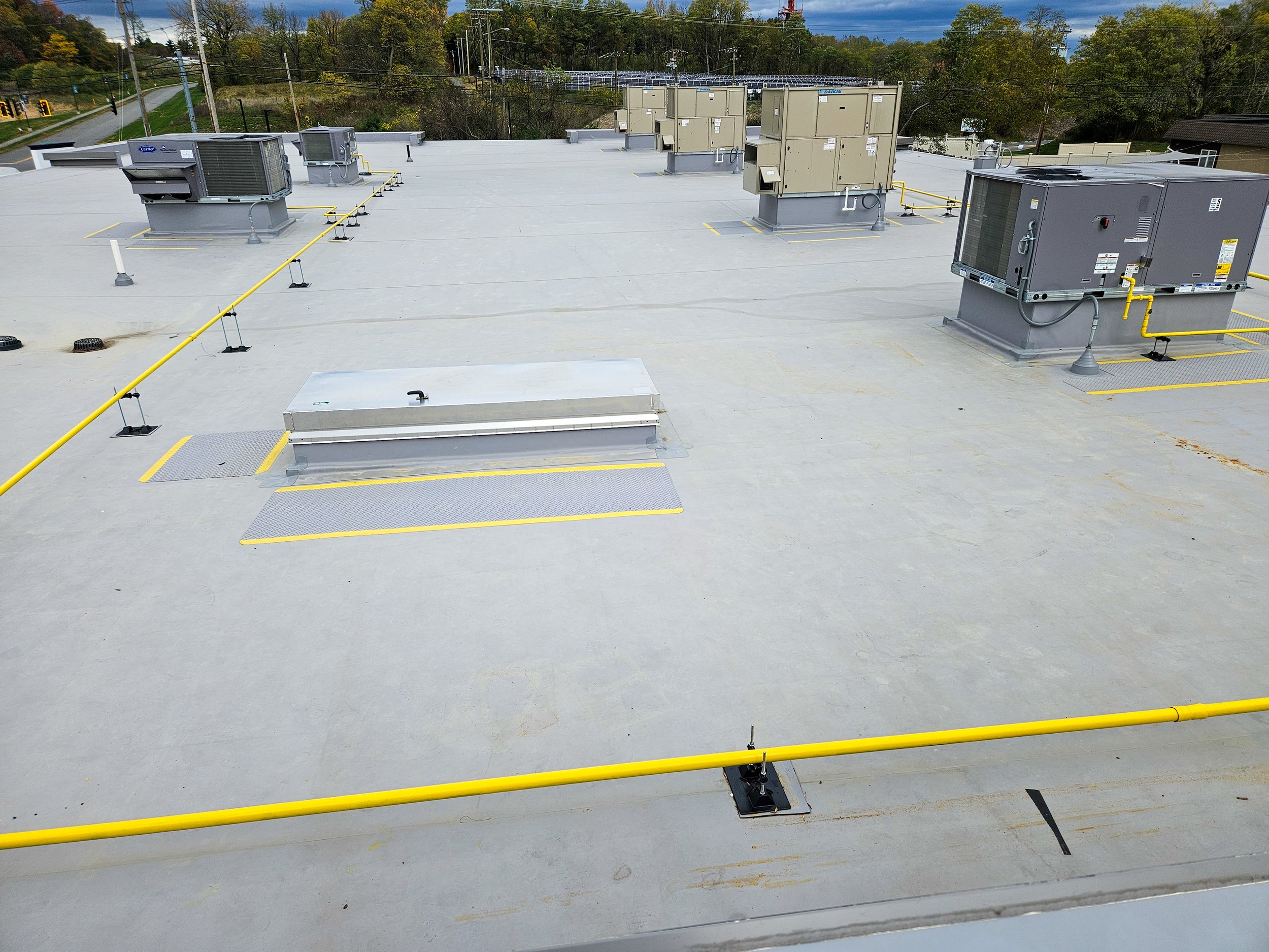 Rooftop HVAC units and safety barriers on a commercial building roof.