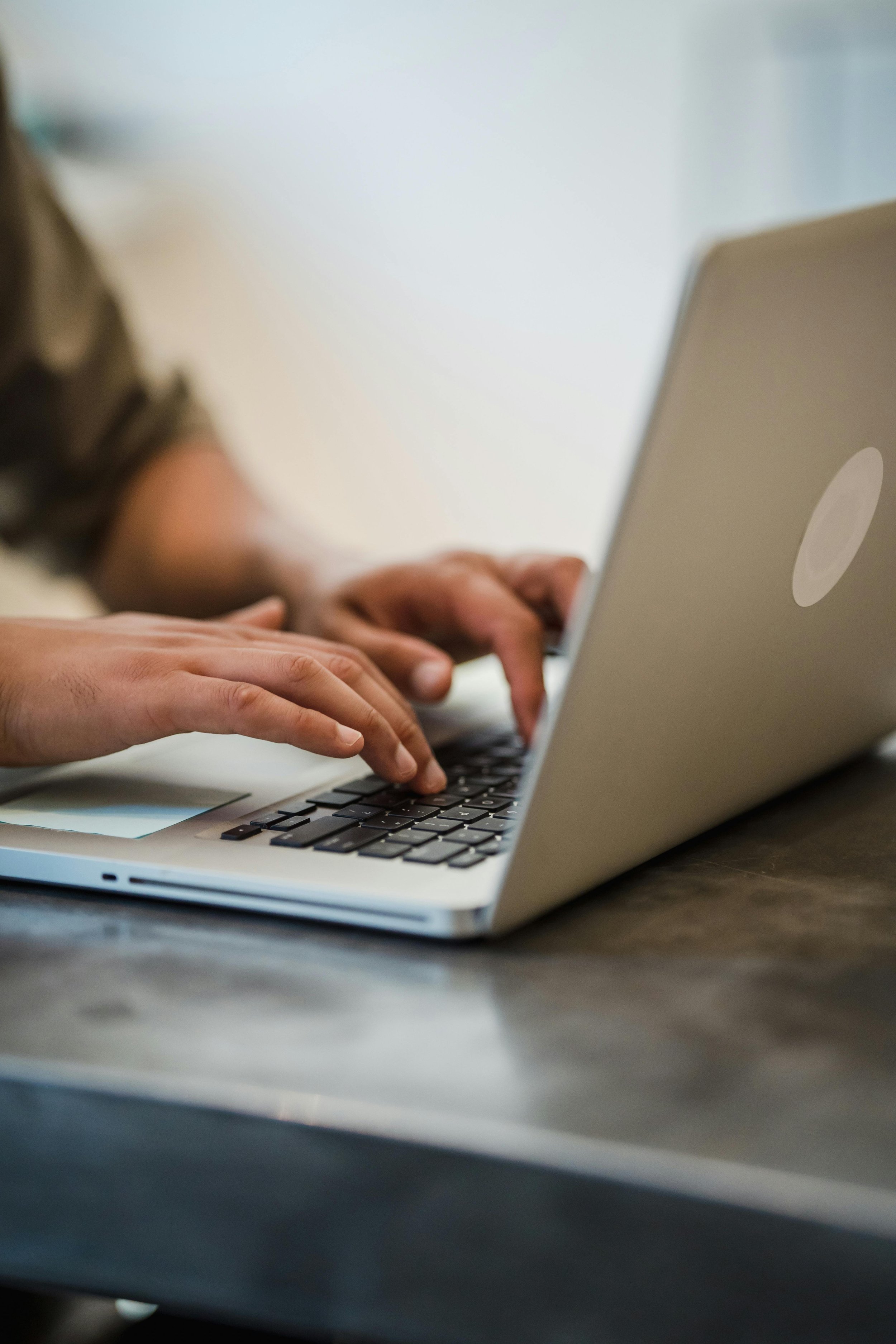 Hands typing on a laptop
