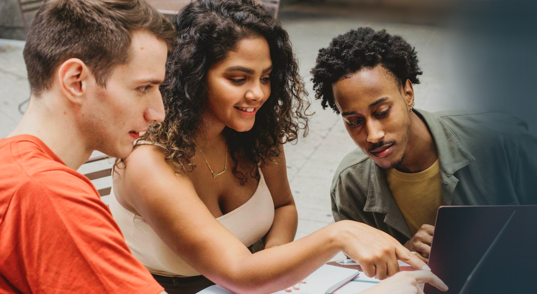 Three students looking at a laptop together