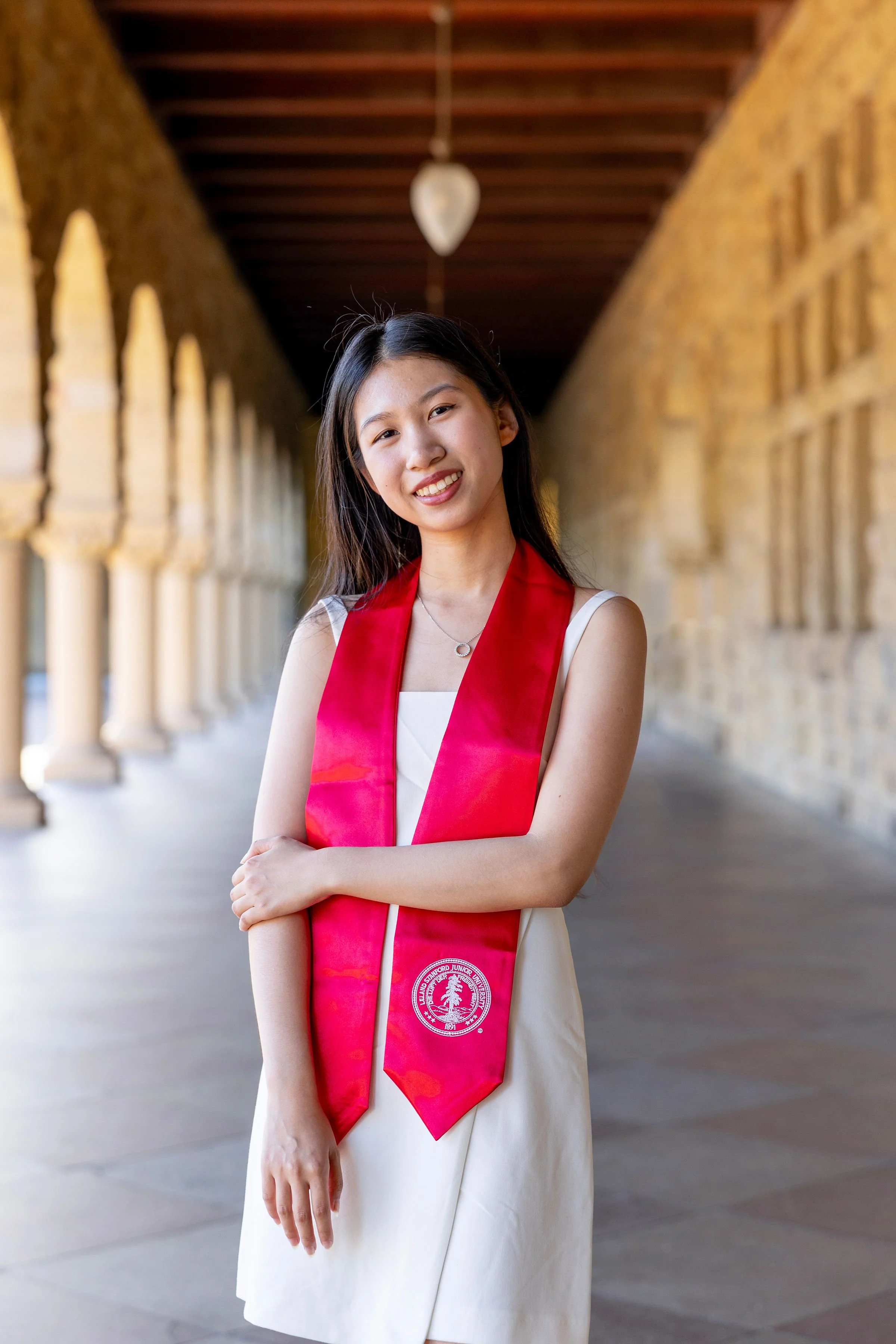 Last Mile awardee Flora H. wearing a graduation stole in a Stanford archway