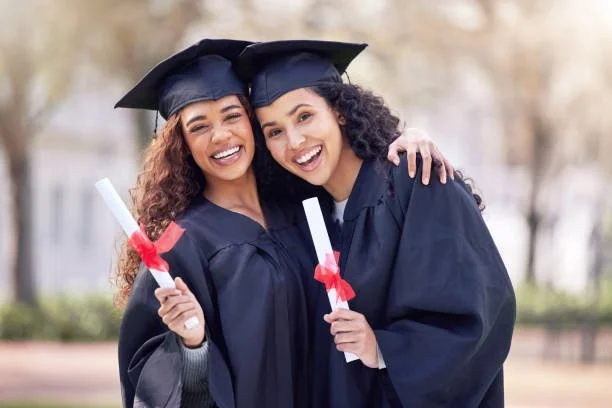 Two graduates hugging and holding diplomas