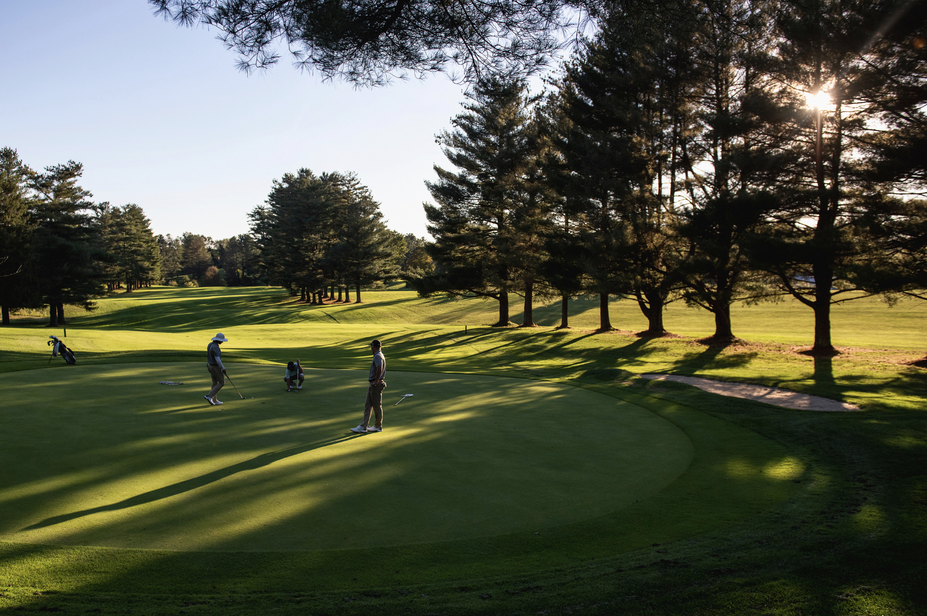 Ohio Universiry golfer Tanner Johnson (center) lines up his putt on hole six of the Athens Country Club as his team members Felipe Darquca (right) and Matt Daulton (left) wartch on Sept. 24. 2021. | Tanner Pearson
