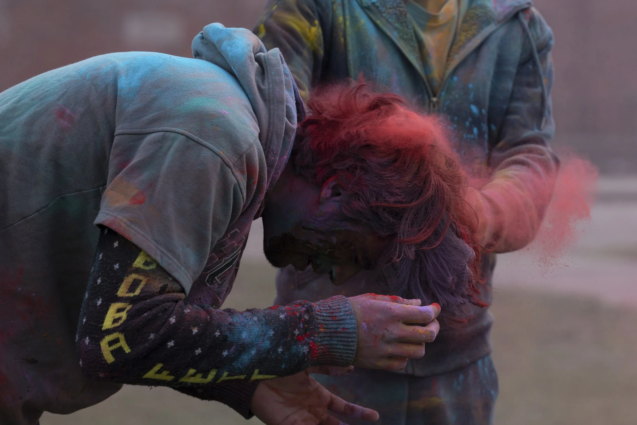 Harshwardan celebrates Holi with other members of the Athens community by throwing colored powder at each other on Ohio University's South Green on March 4,
2023 Harshwardan's friend pours red powder in his hair. | Megan VanVlack