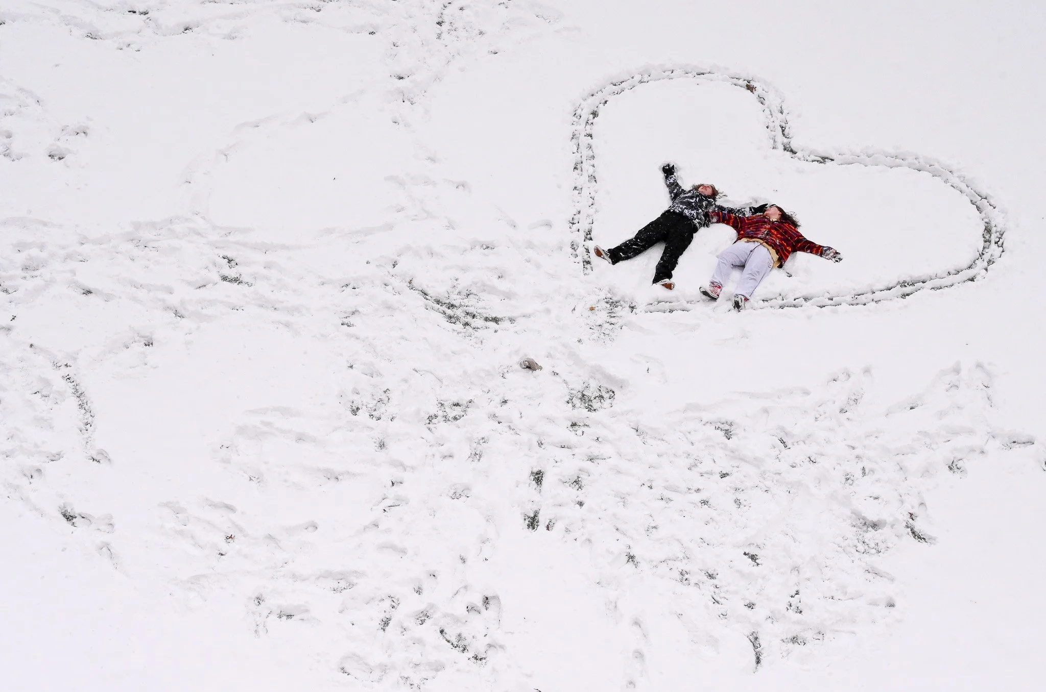 Olivia Rose, left, and Alexis Scales, right, play in the snow behind Adams Hall at Ohio University on Friday, Jan. 19, 2024. After receiving an email announcing the cancellation of all classes due to the weather, the couple took advantage of the snow